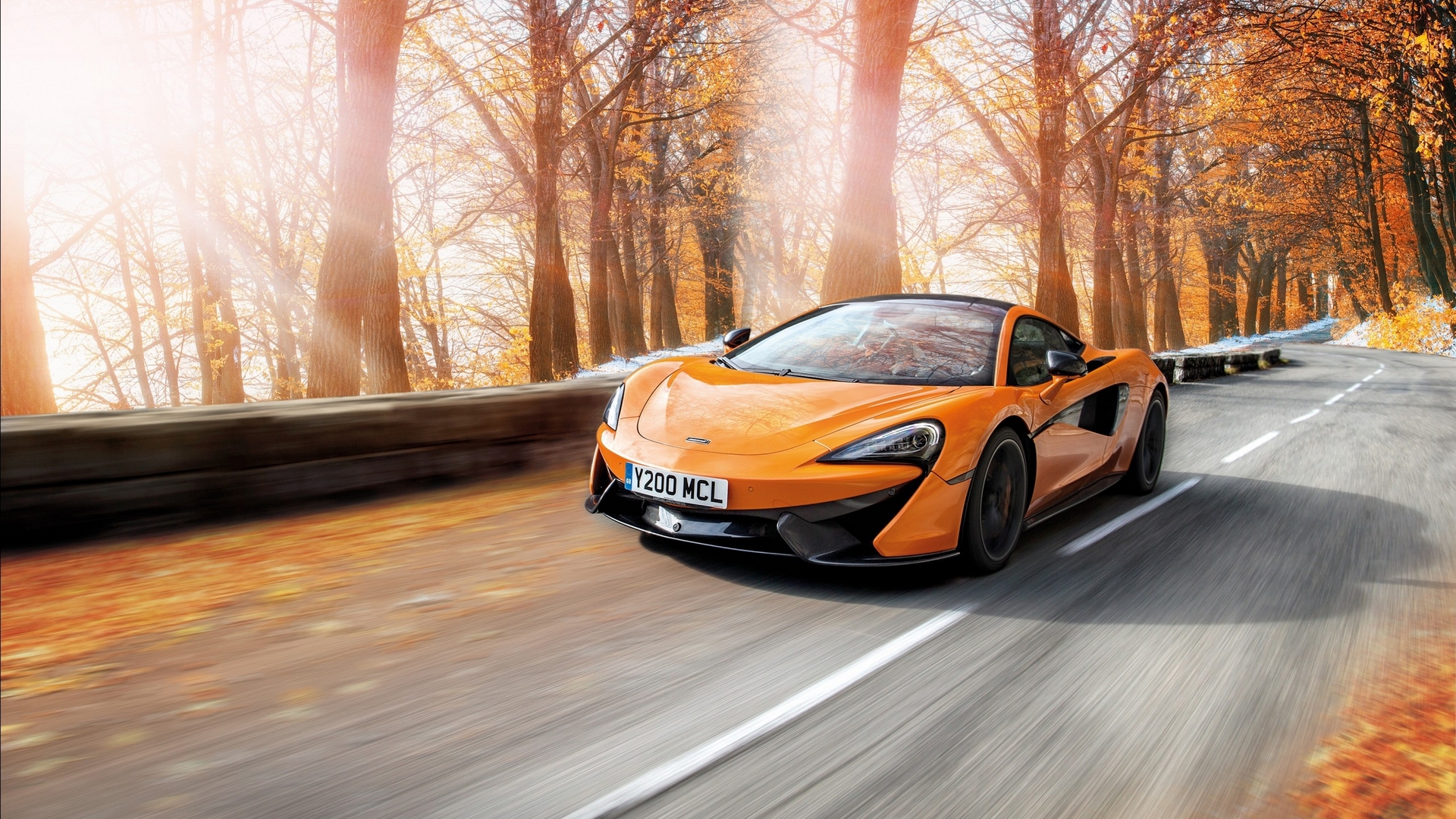 Orange McLaren driving on a road in autumn HD Wallpaper