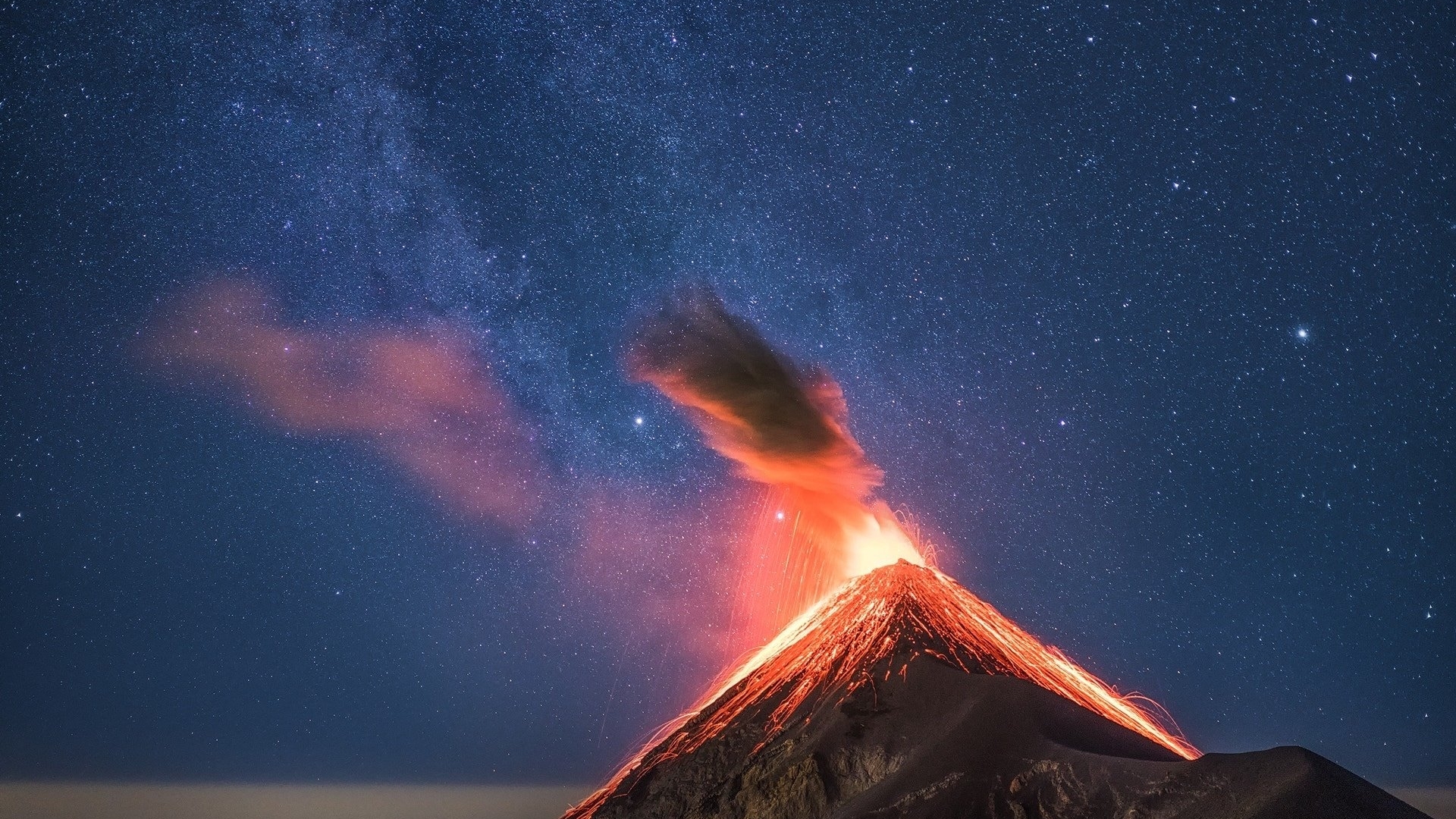 Volcano erupting under a starry night sky HD Wallpaper