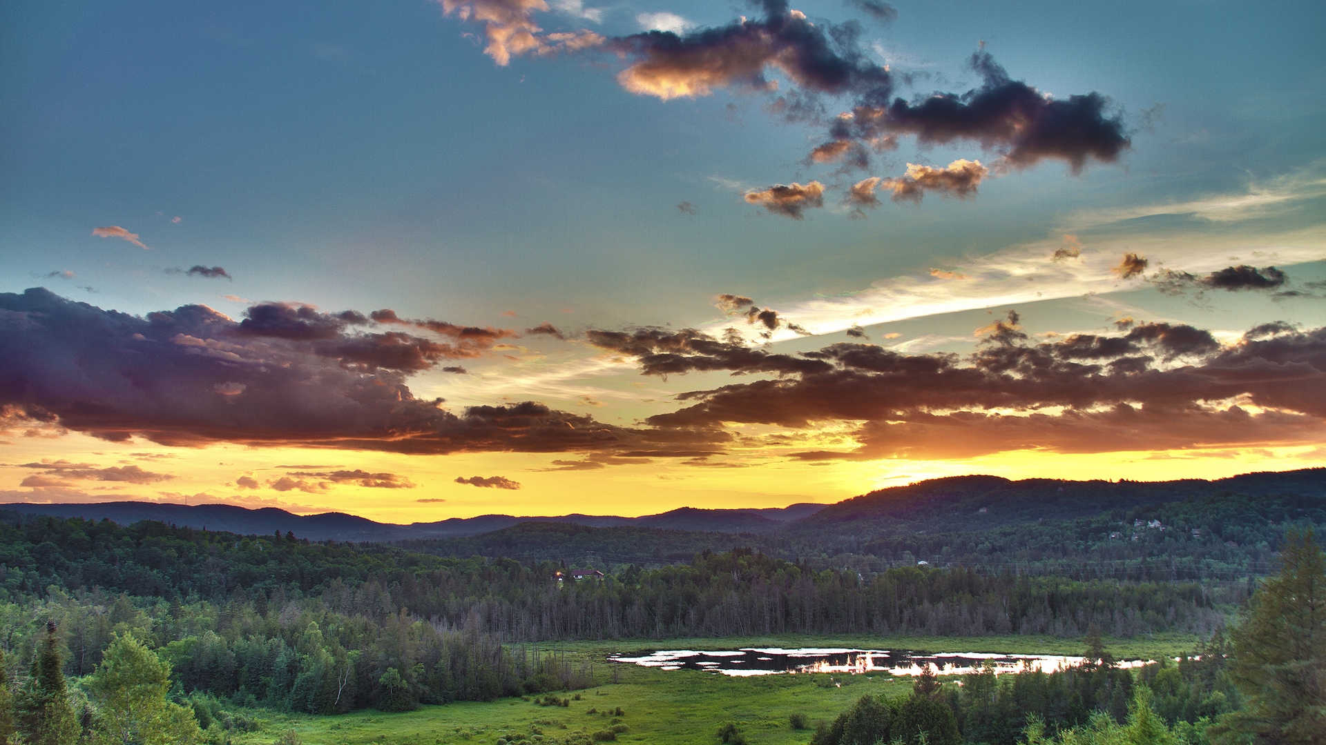 Sunset over a forest with a pond and mountains HD Wallpaper