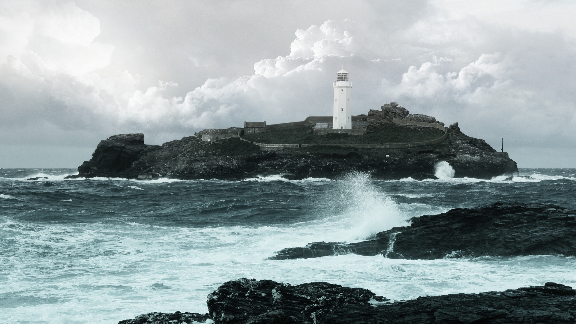 Lighthouse on a rocky island in stormy seas HD Wallpaper