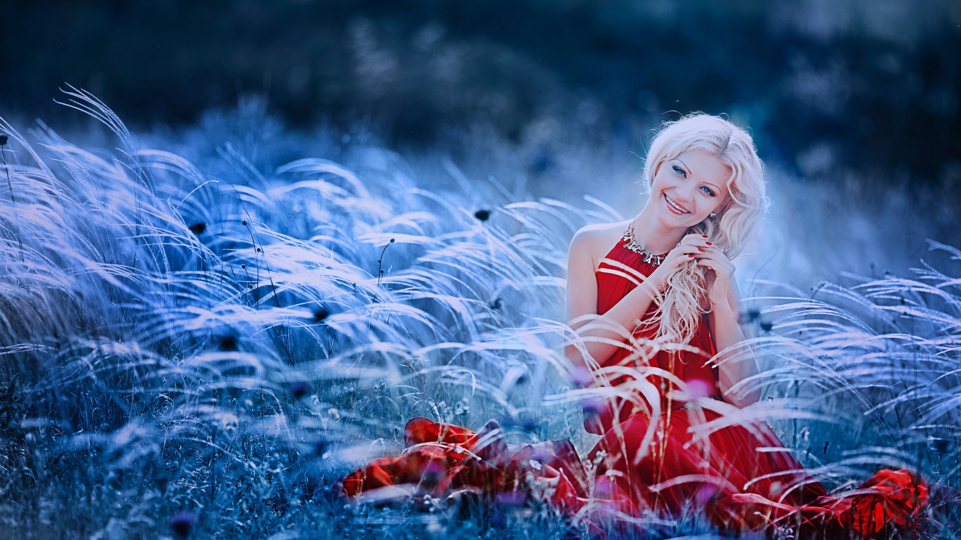Woman in red dress sitting in a field of grass HD Wallpaper
