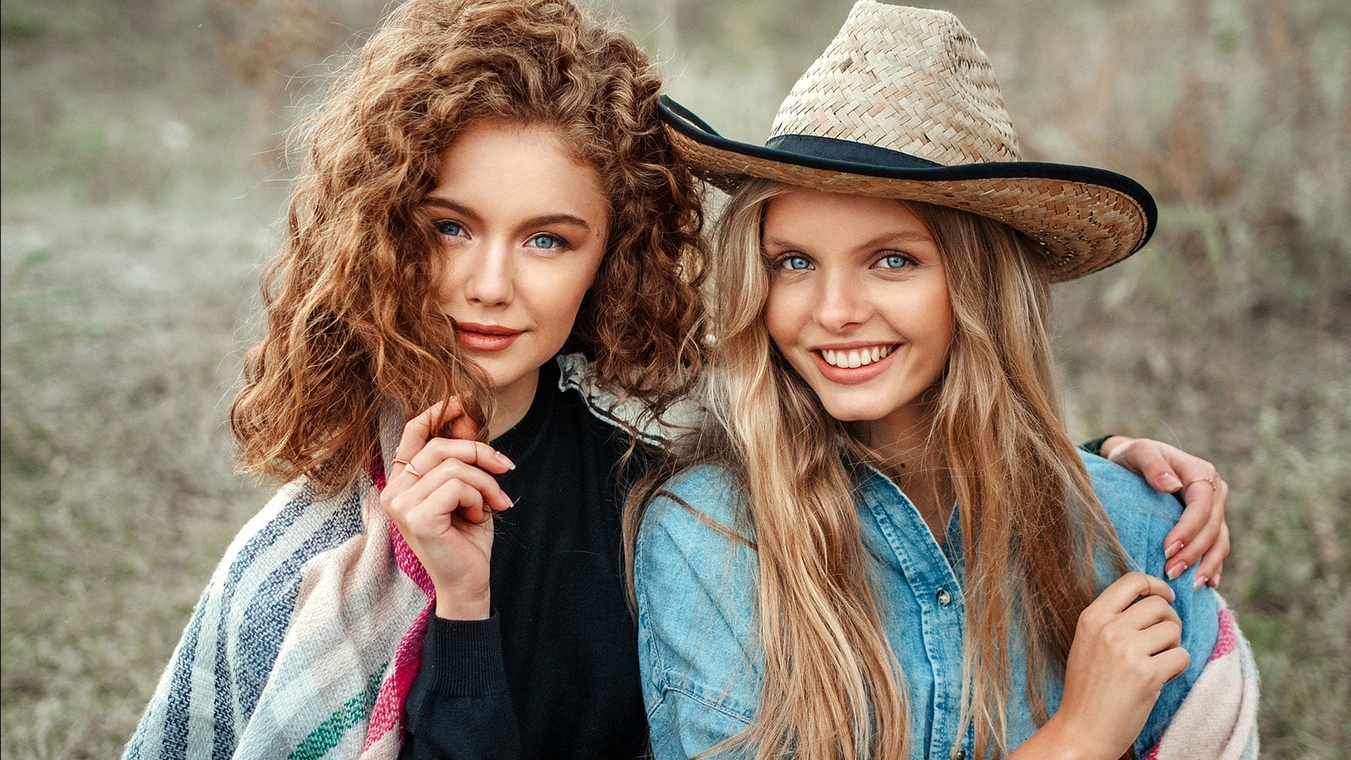 Two young women, one with curly red hair and the other with blonde hair wearing a straw hat HD Wallpaper