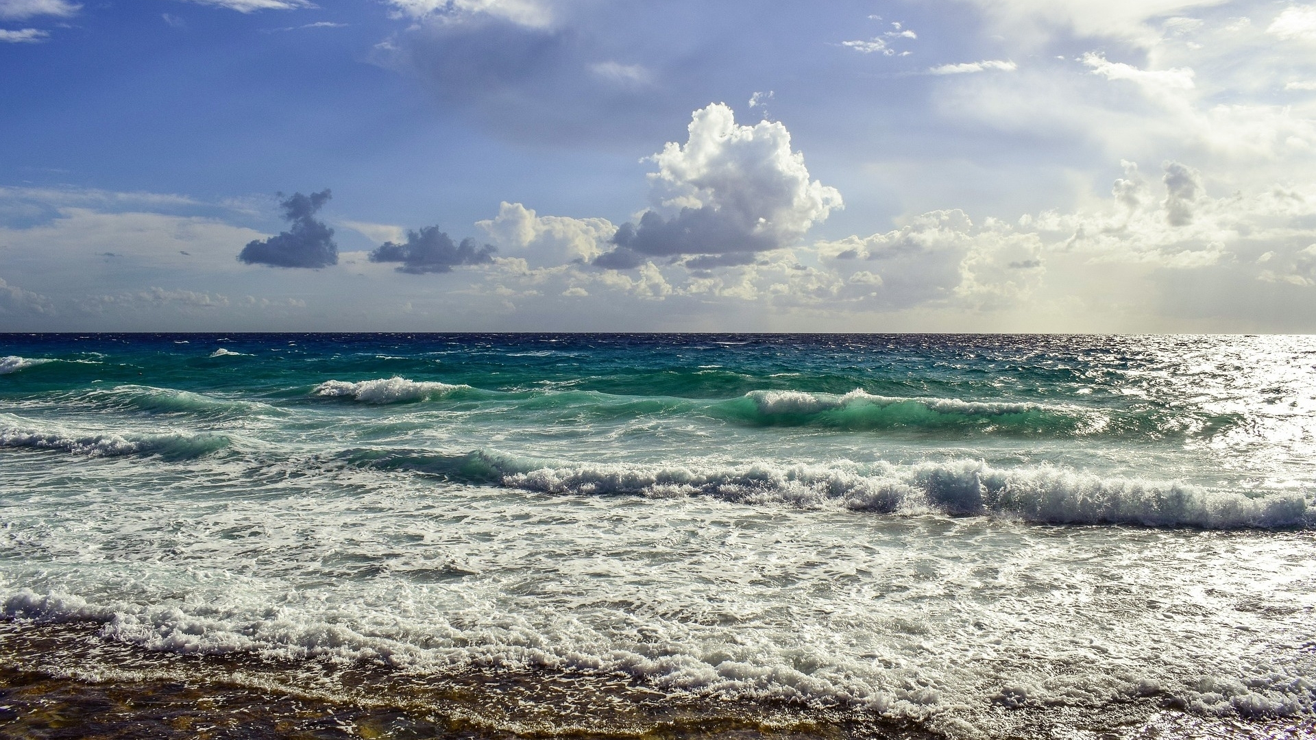 Ocean waves crashing on the shore under a cloudy sky HD Wallpaper