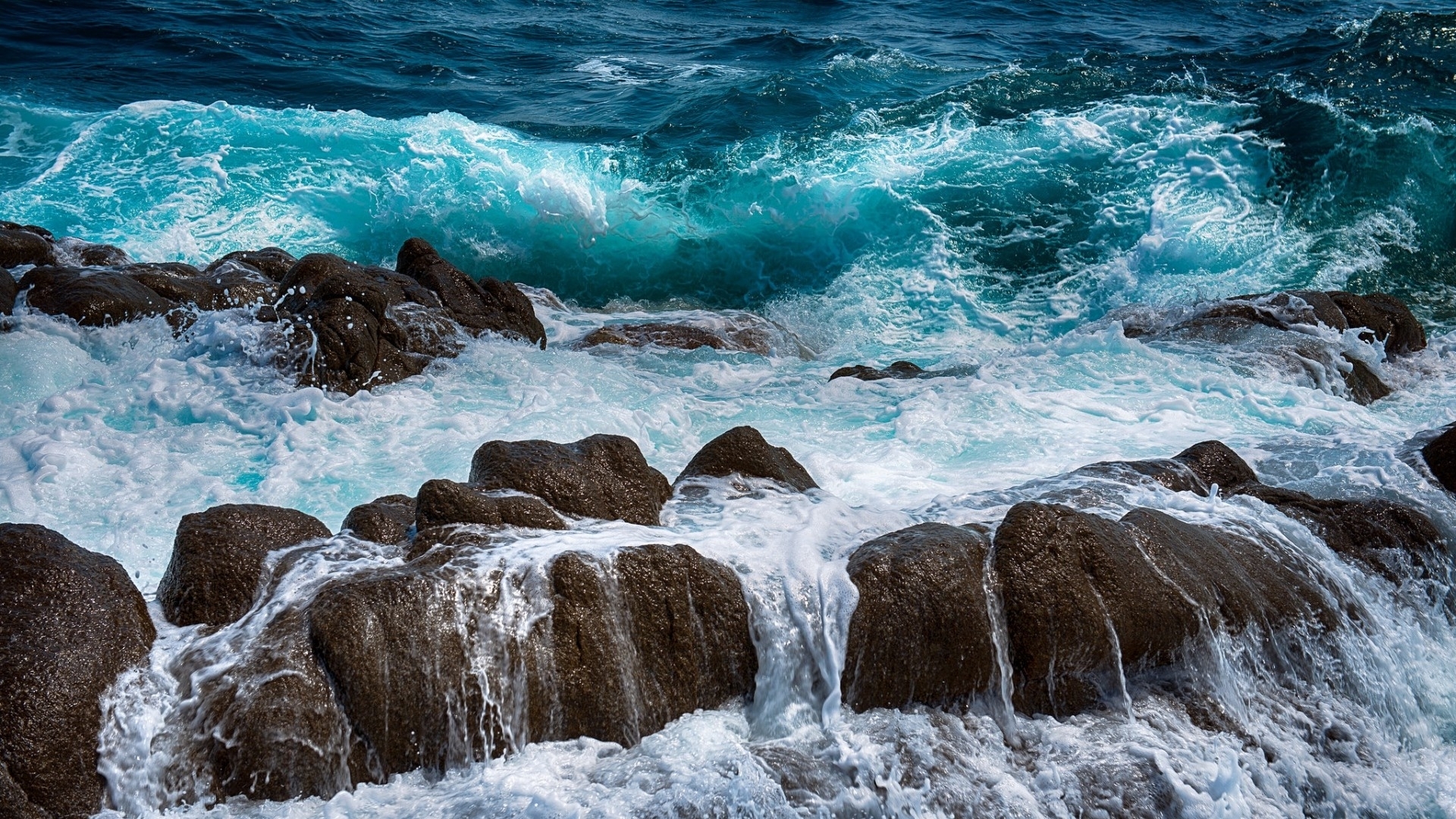 Turquoise ocean waves crashing on dark rocks HD Wallpaper