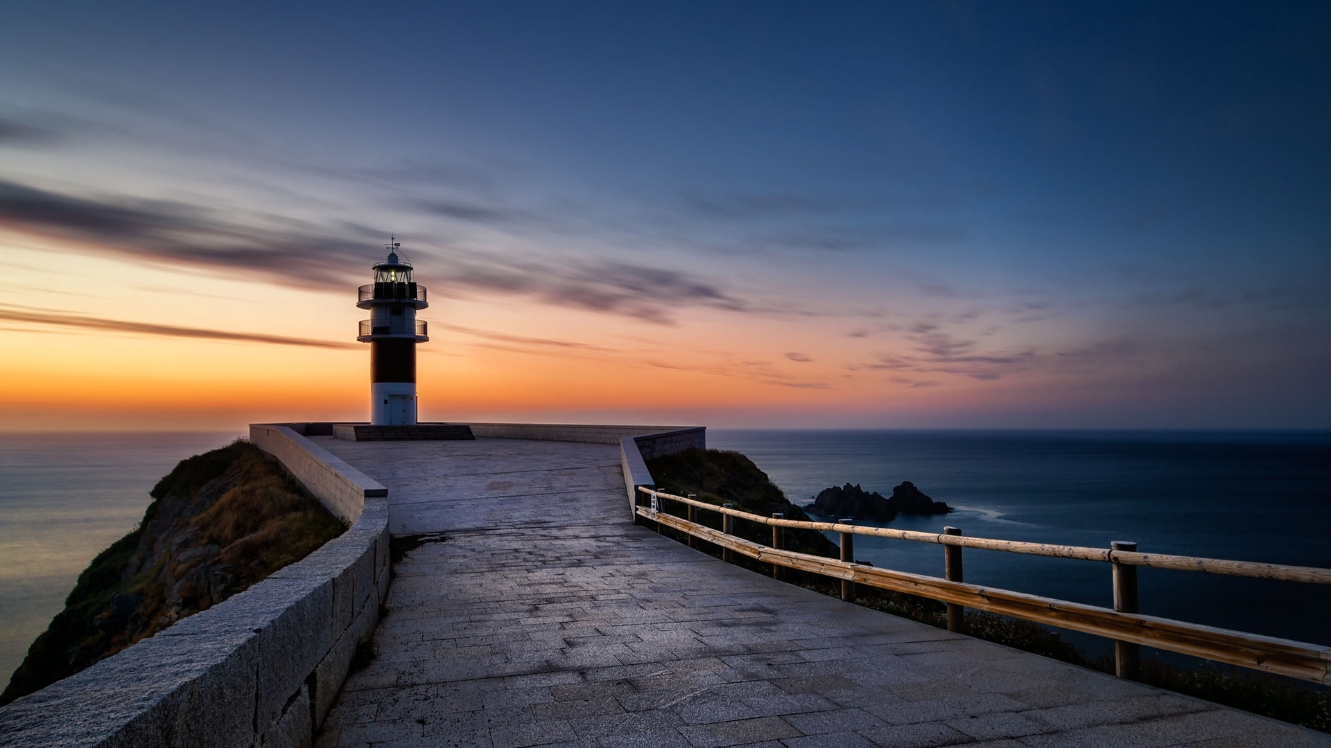 Lighthouse on a cliff overlooking the sea at sunset HD Wallpaper