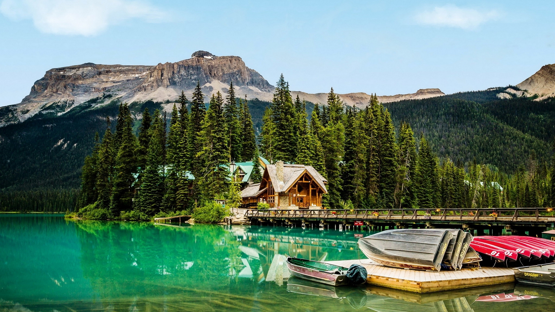 Wooden cabin by a lake with boats and mountains HD Wallpaper