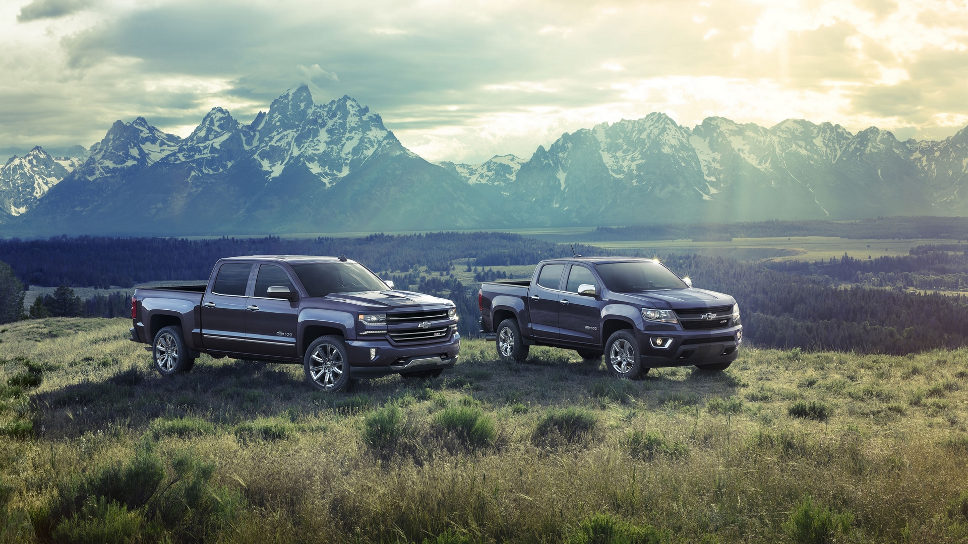 Two Chevrolet trucks in front of mountains HD Wallpaper