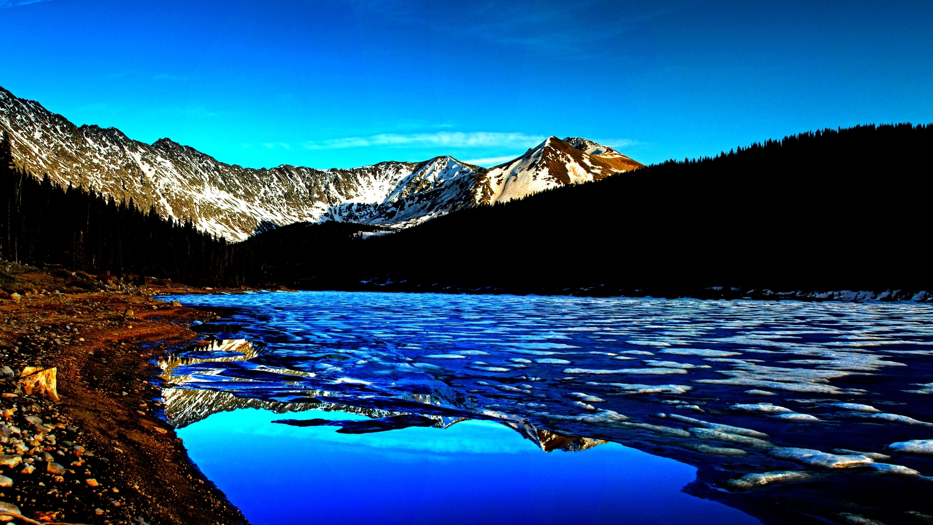 Snow-capped mountains reflected in a partially frozen lake HD Wallpaper