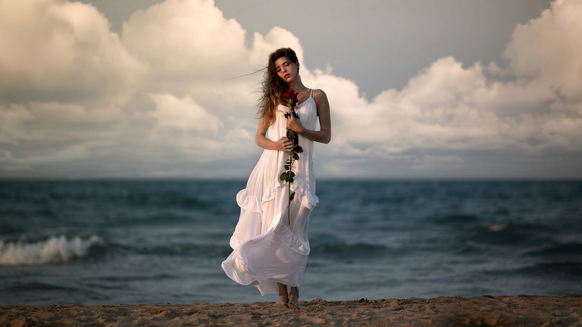 Woman in white dress holding a red rose on a beach HD Wallpaper