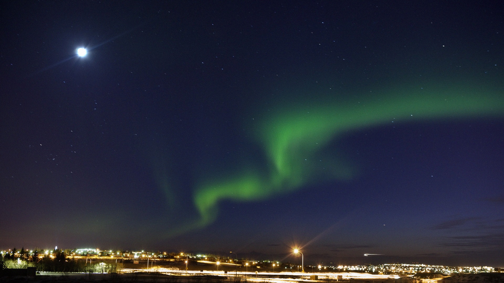 Aurora Borealis over a city at night HD Wallpaper
