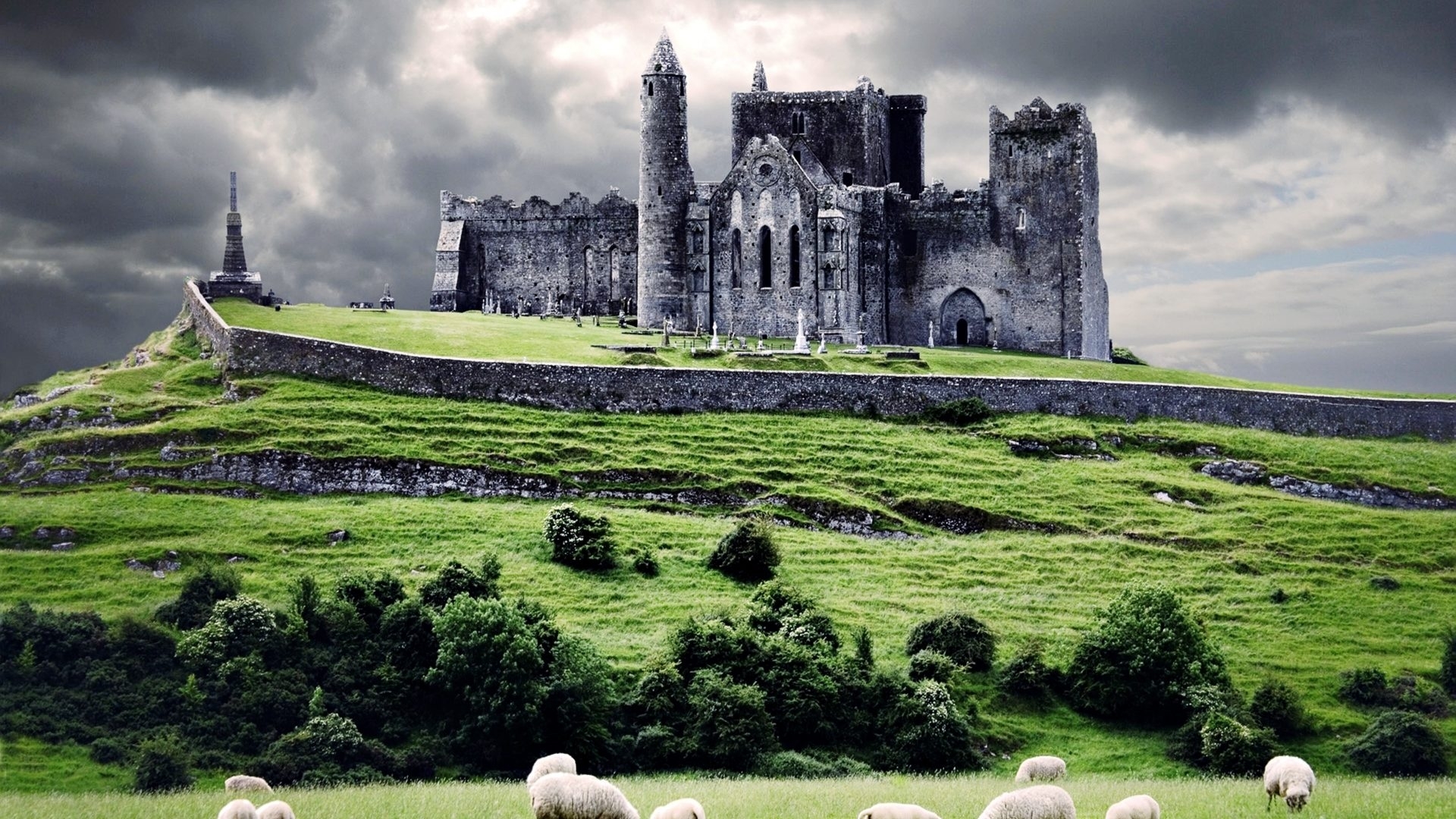 Castle on a grassy hill with sheep and stormy clouds HD Wallpaper