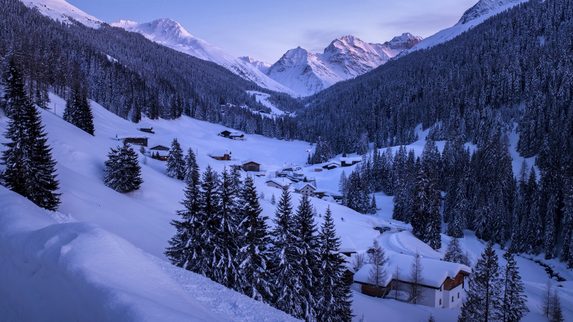 Snowy mountain valley with houses and pine trees HD Wallpaper