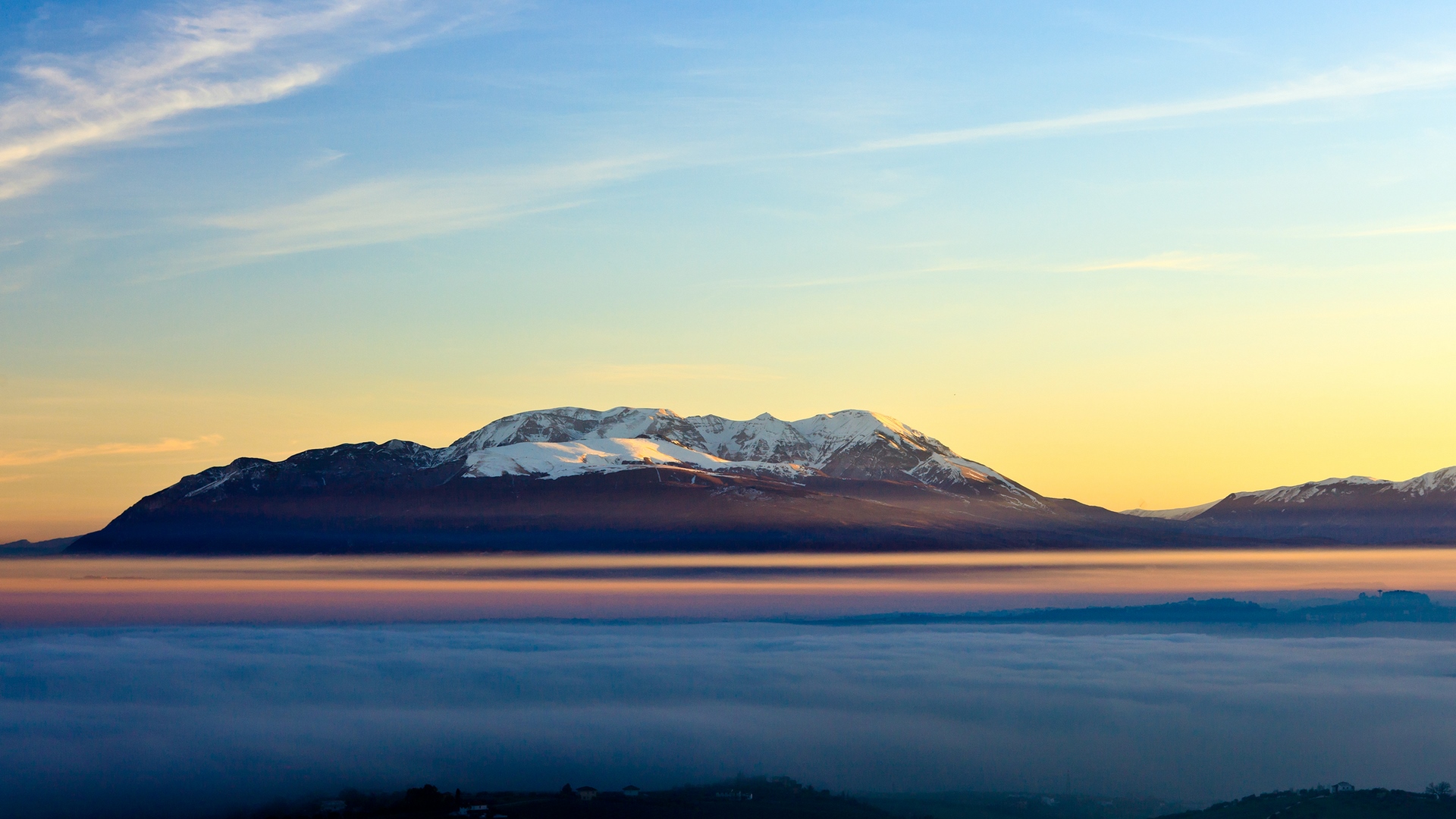 Snow-capped mountains above a foggy valley at sunset HD Wallpaper