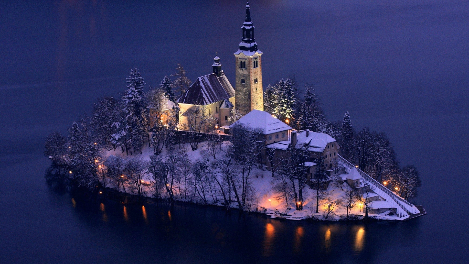 Snow-covered island church at night with lights HD Wallpaper