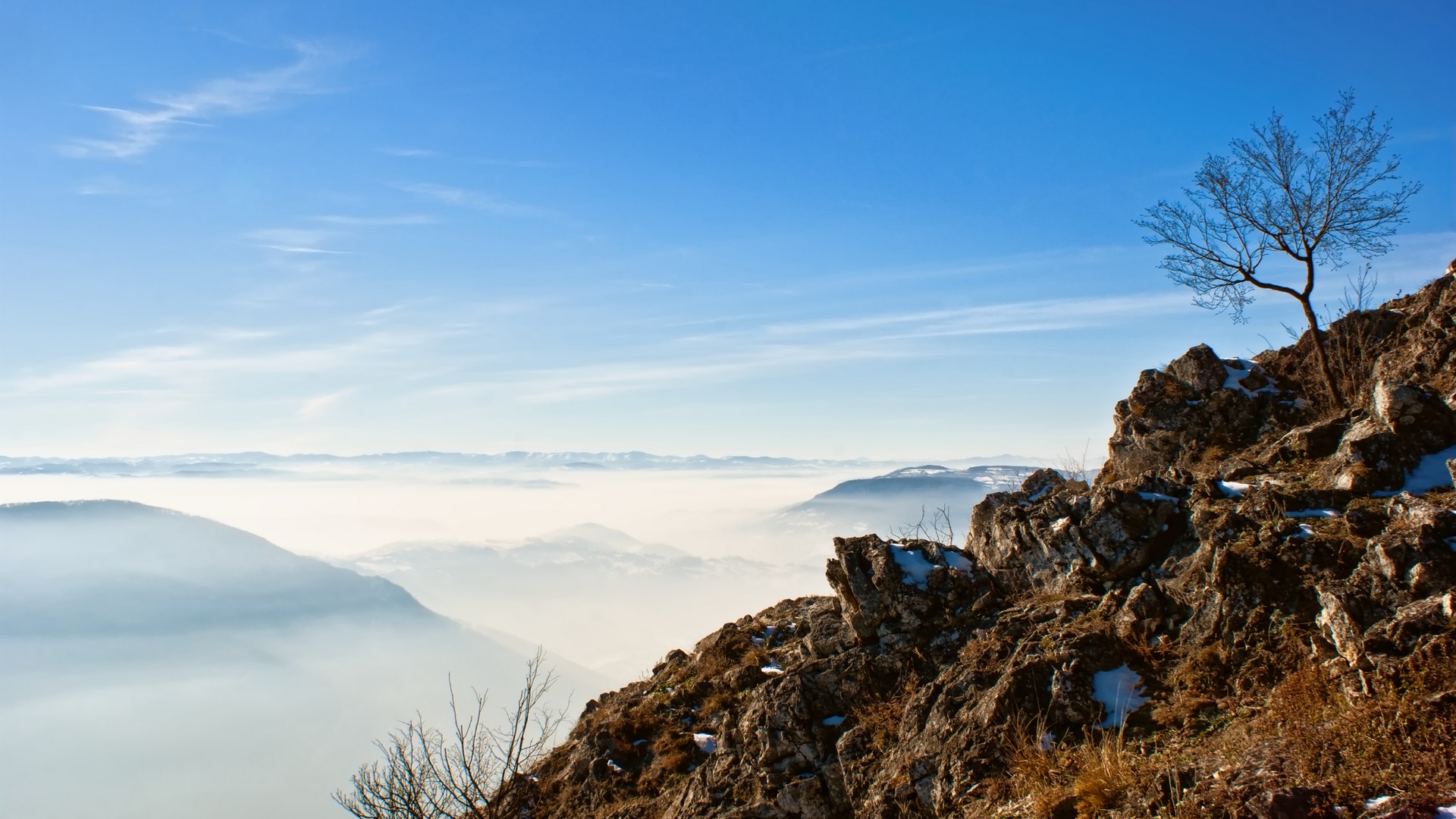 Mountain view over a foggy valley under blue skies HD Wallpaper