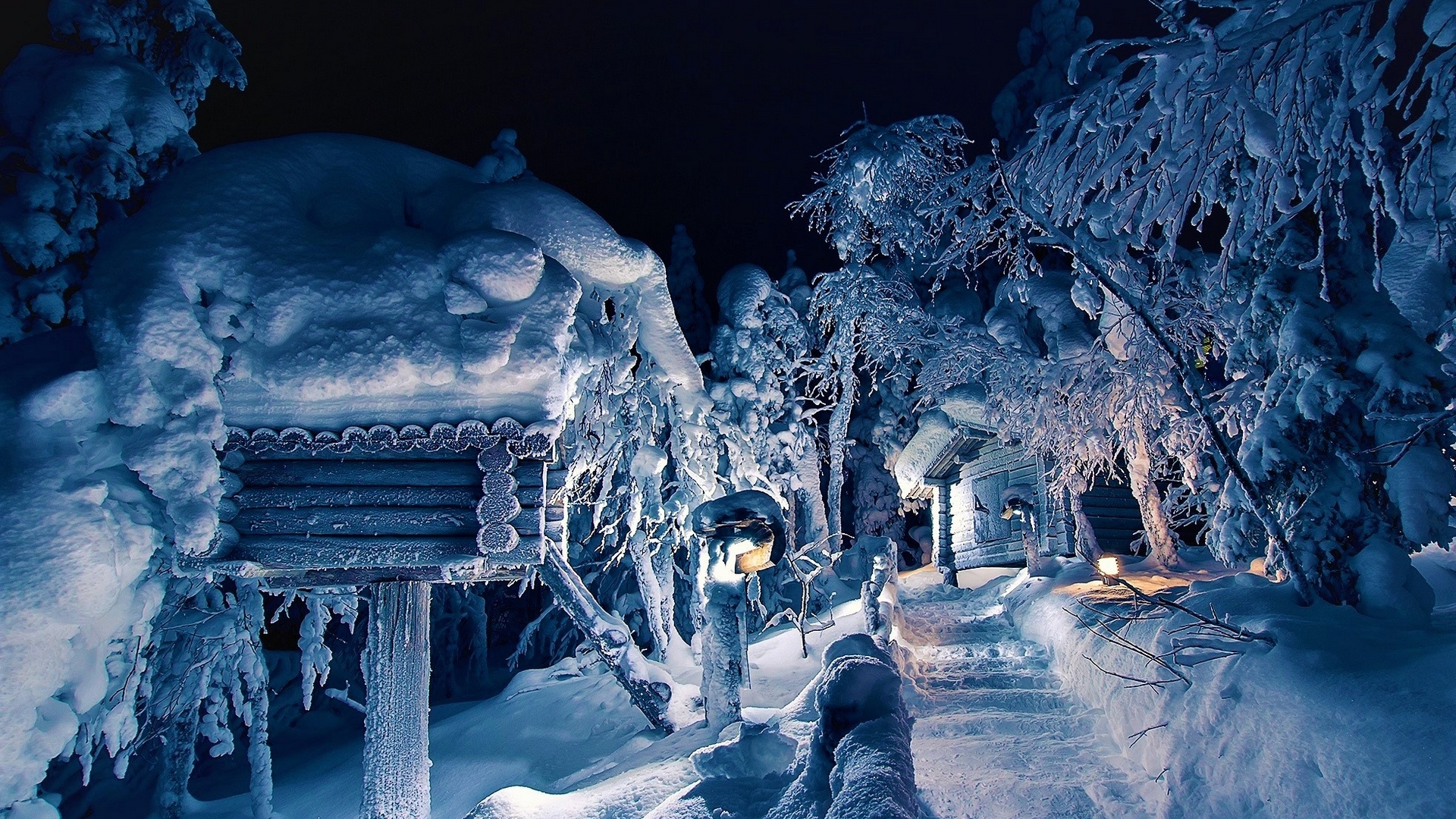 Snow-covered wooden houses and trees at night HD Wallpaper