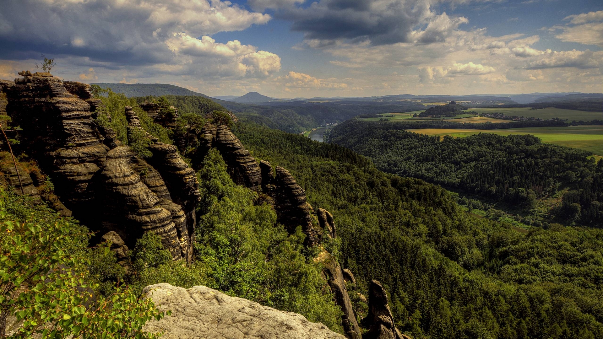 Rocky cliffs overlooking a forested valley and river HD Wallpaper