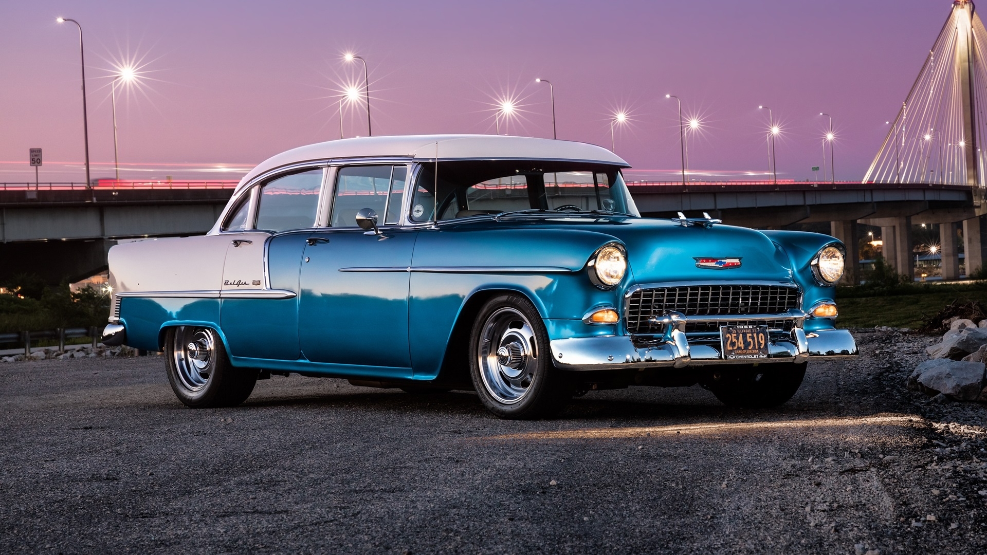 Blue and white 1955 Chevrolet Bel Air parked by a bridge at dusk HD Wallpaper