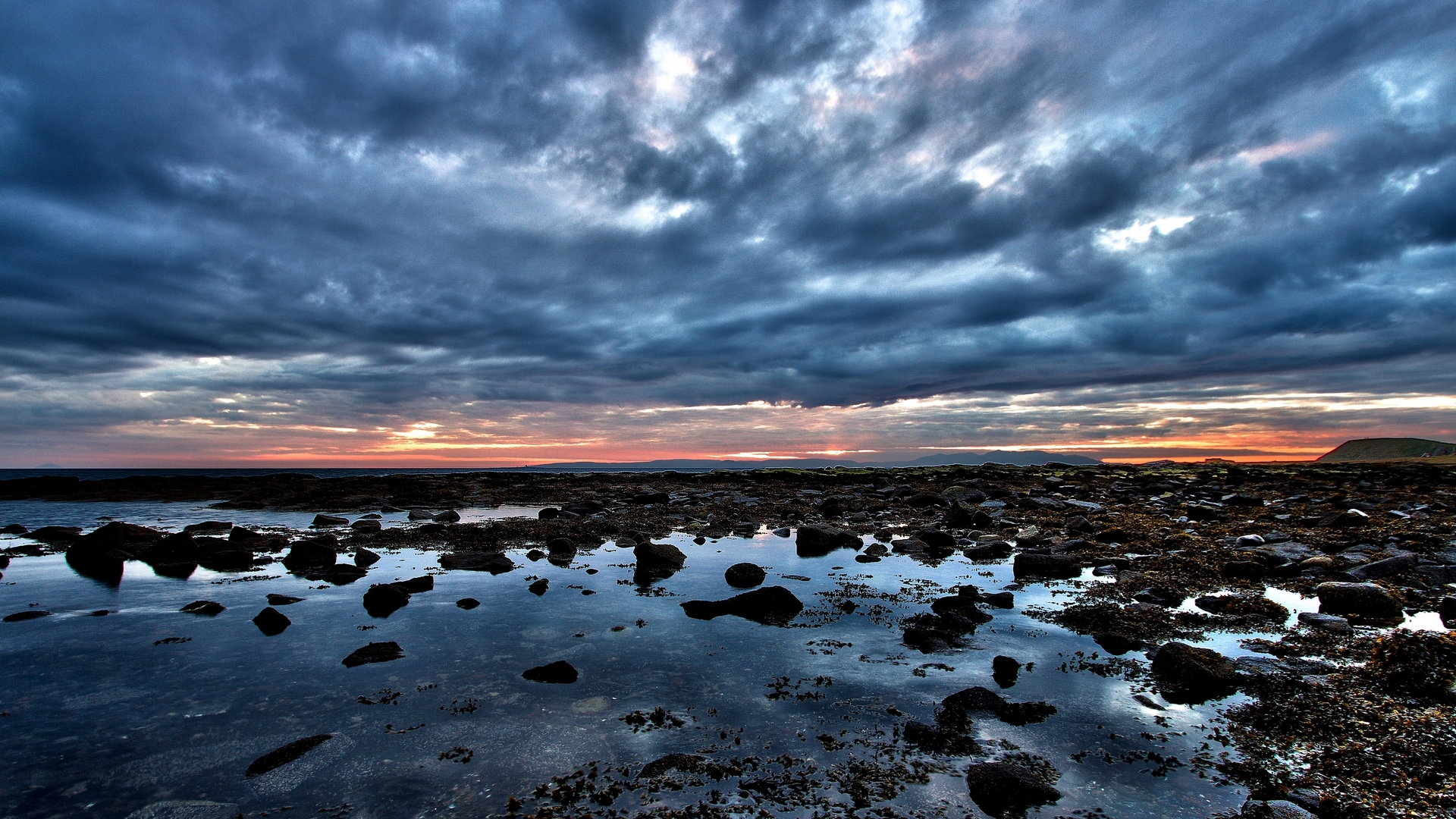 Rocky shore with tide pools at sunset under cloudy sky HD Wallpaper