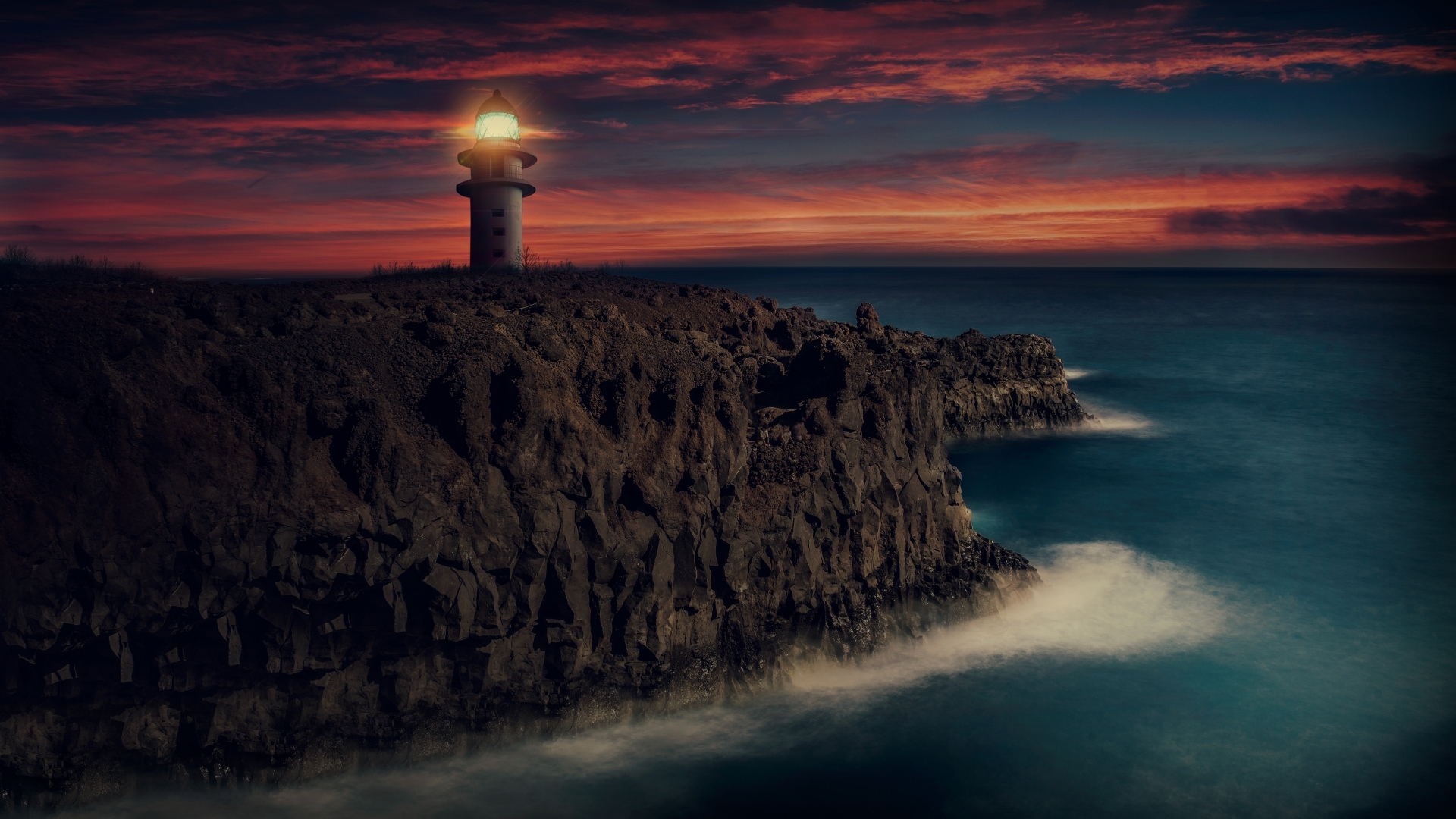 Lighthouse on a rocky cliff at sunset HD Wallpaper