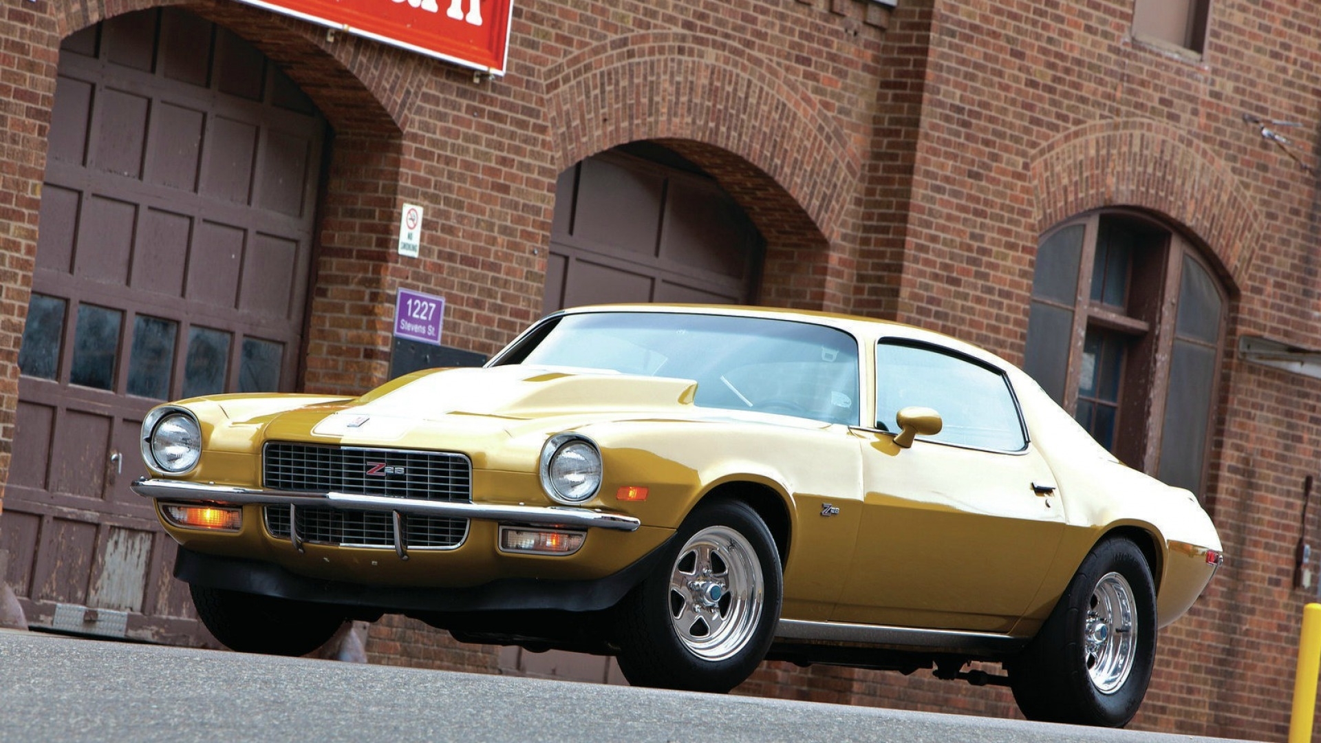 Gold Chevrolet Camaro Z28 parked in front of brick building HD Wallpaper