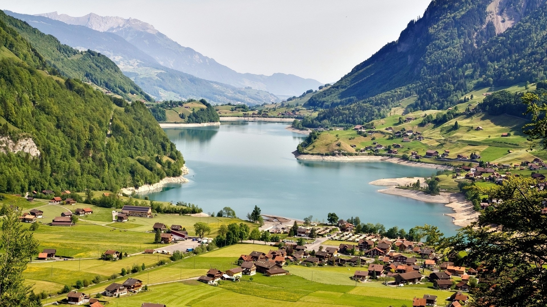 Lake and village nestled in a mountain valley HD Wallpaper