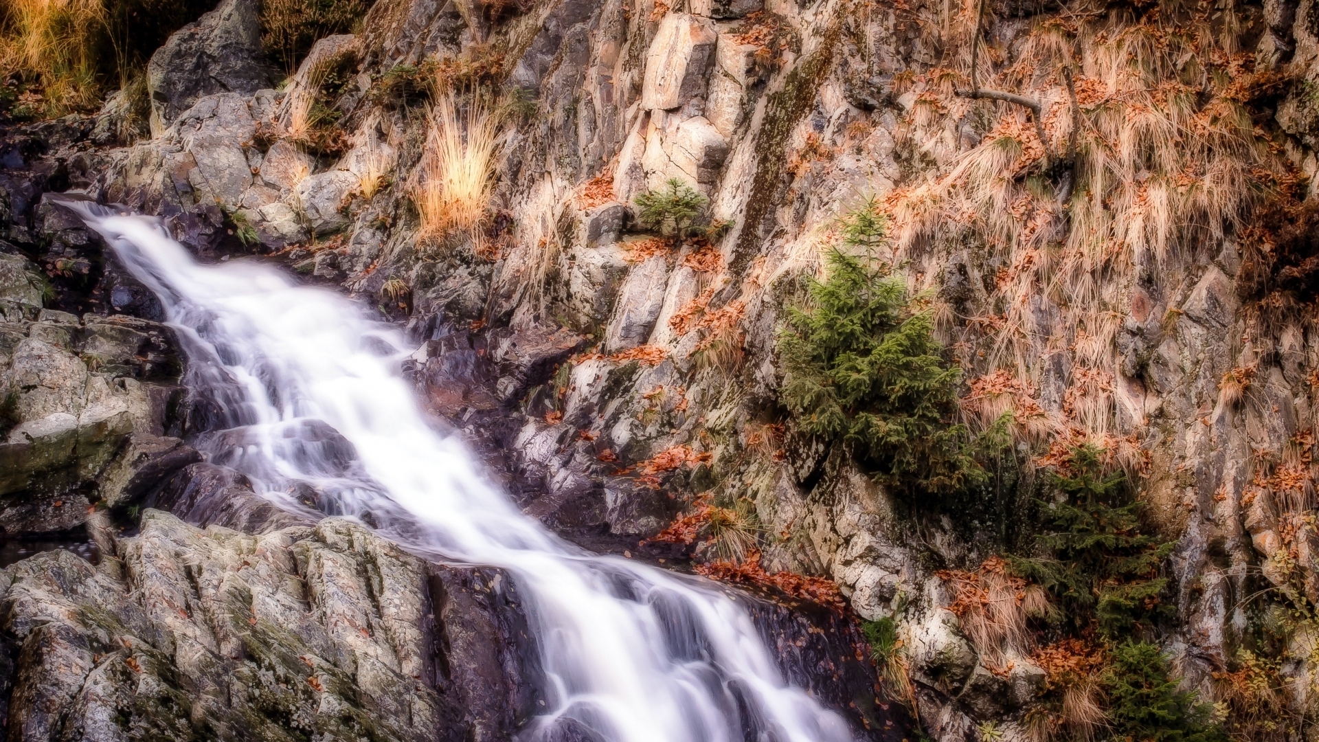 Waterfall cascading over rocky mountain slope with autumn foliage HD Wallpaper