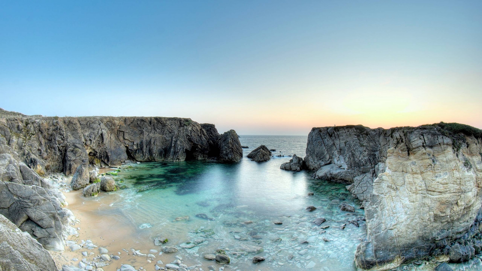 Rocky cove with clear turquoise water and sandy beach HD Wallpaper