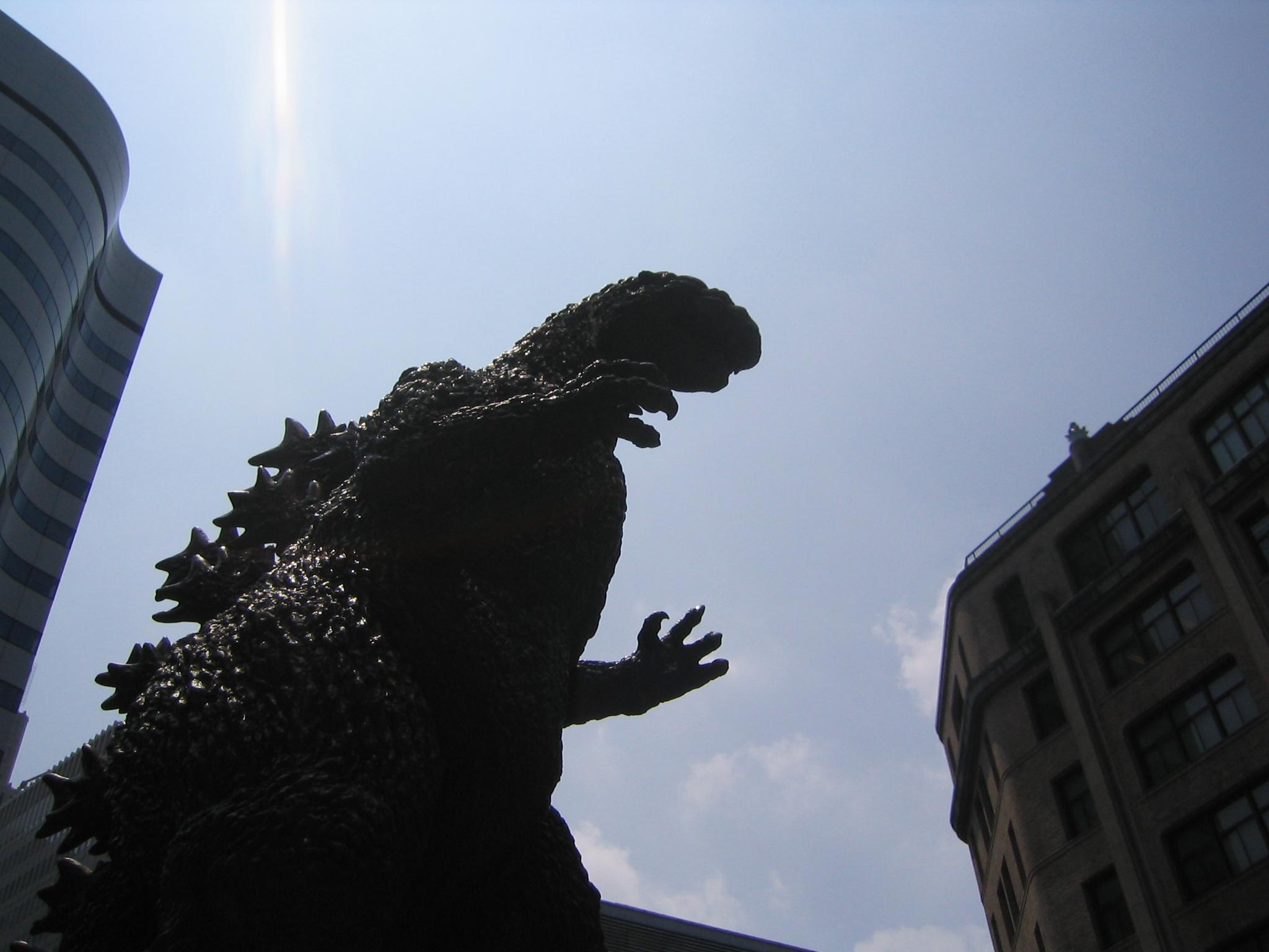Godzilla statue in front of buildings HD Wallpaper