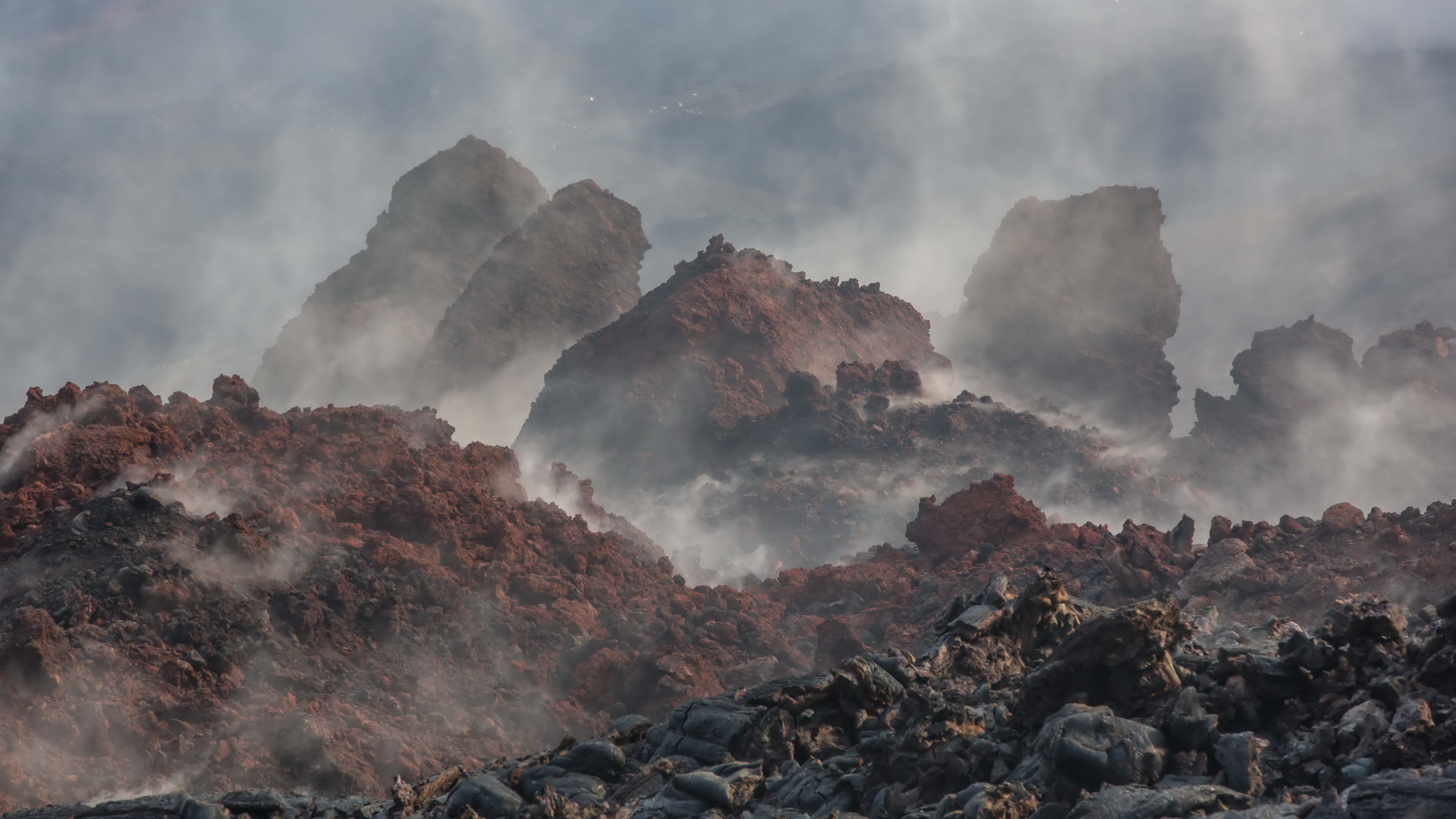 Volcanic landscape with steam and rock formations HD Wallpaper