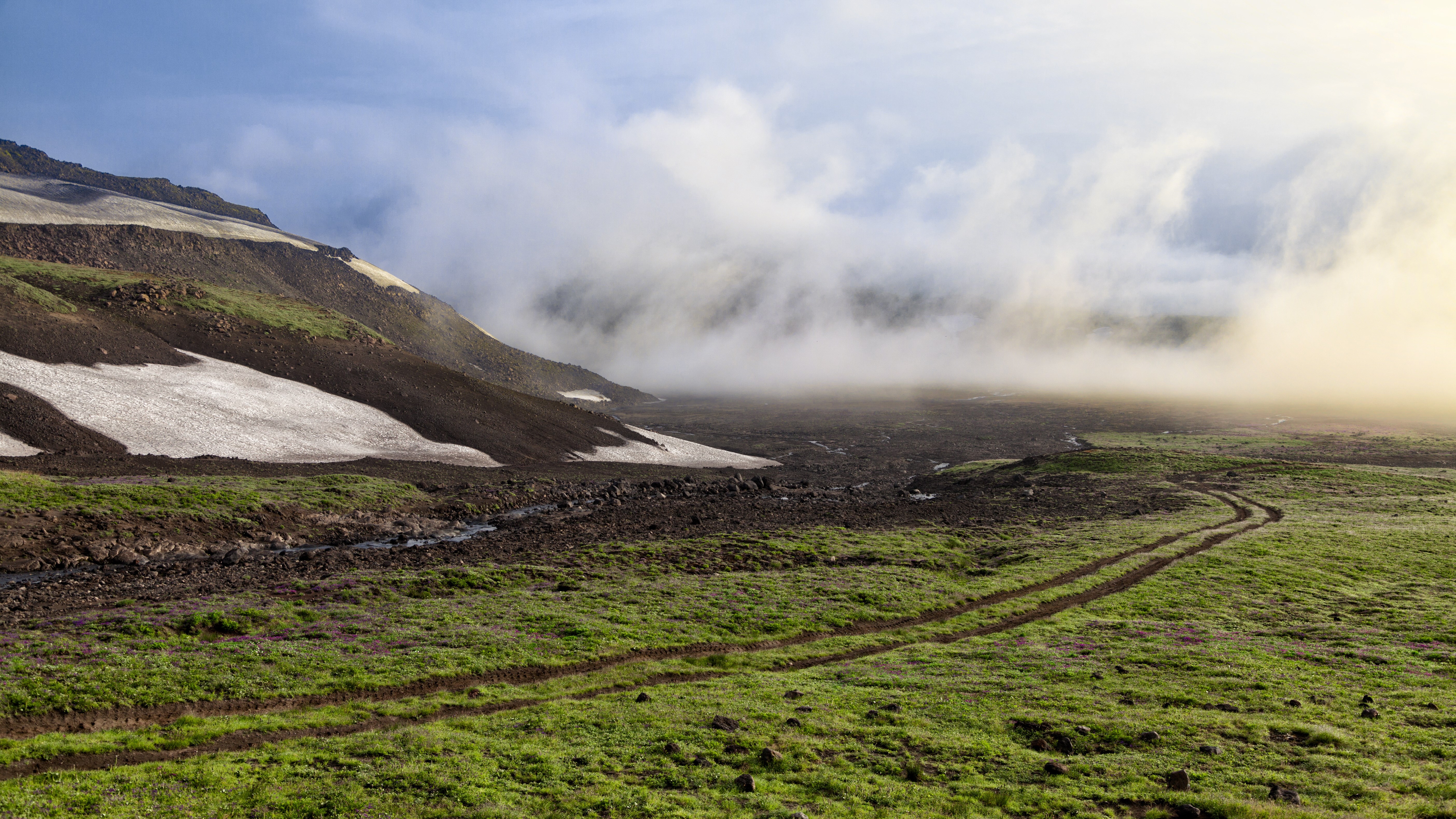 Mountainous landscape with snow patches and fog HD Wallpaper
