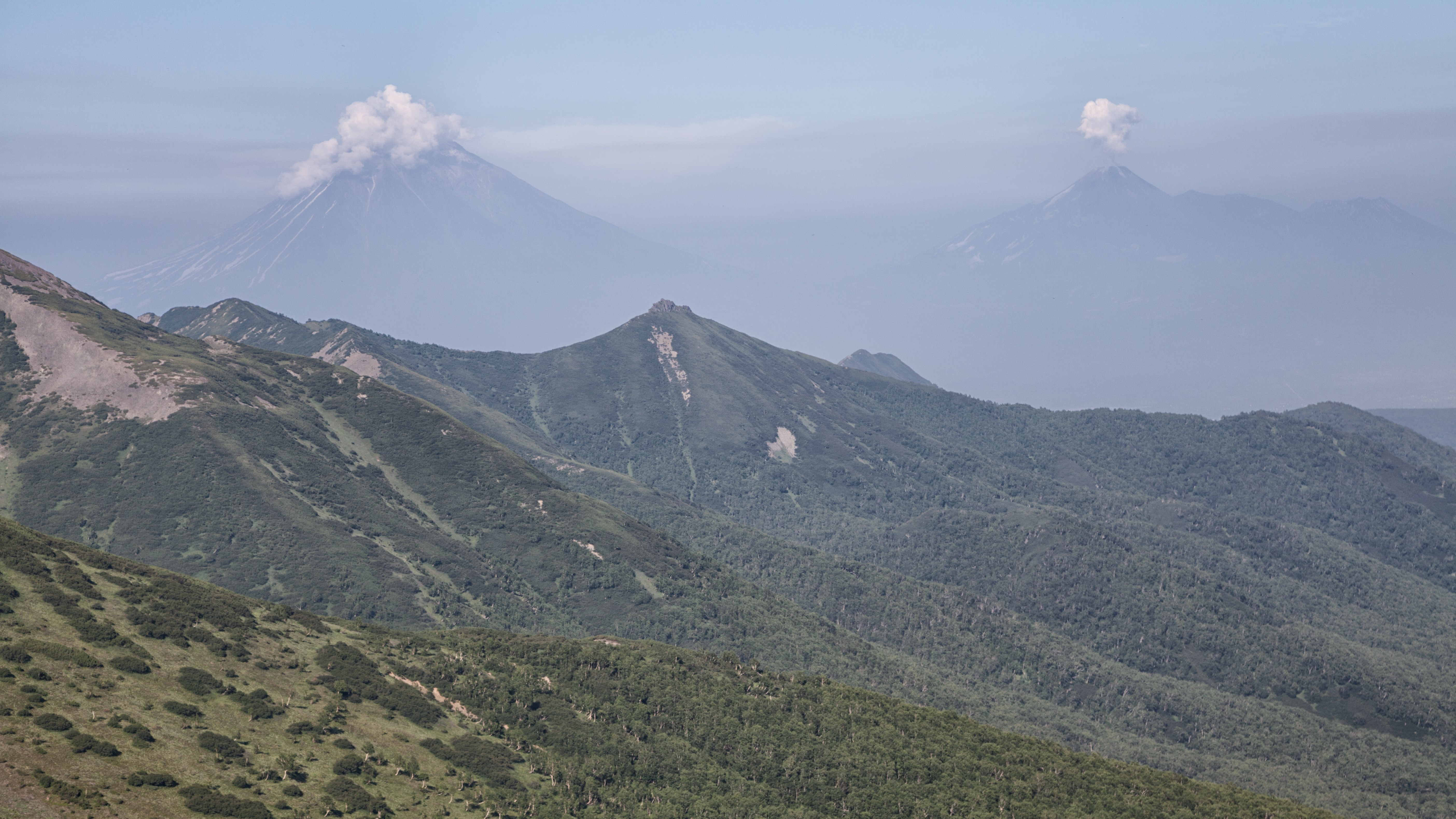 Volcanoes erupting in a mountainous landscape HD Wallpaper