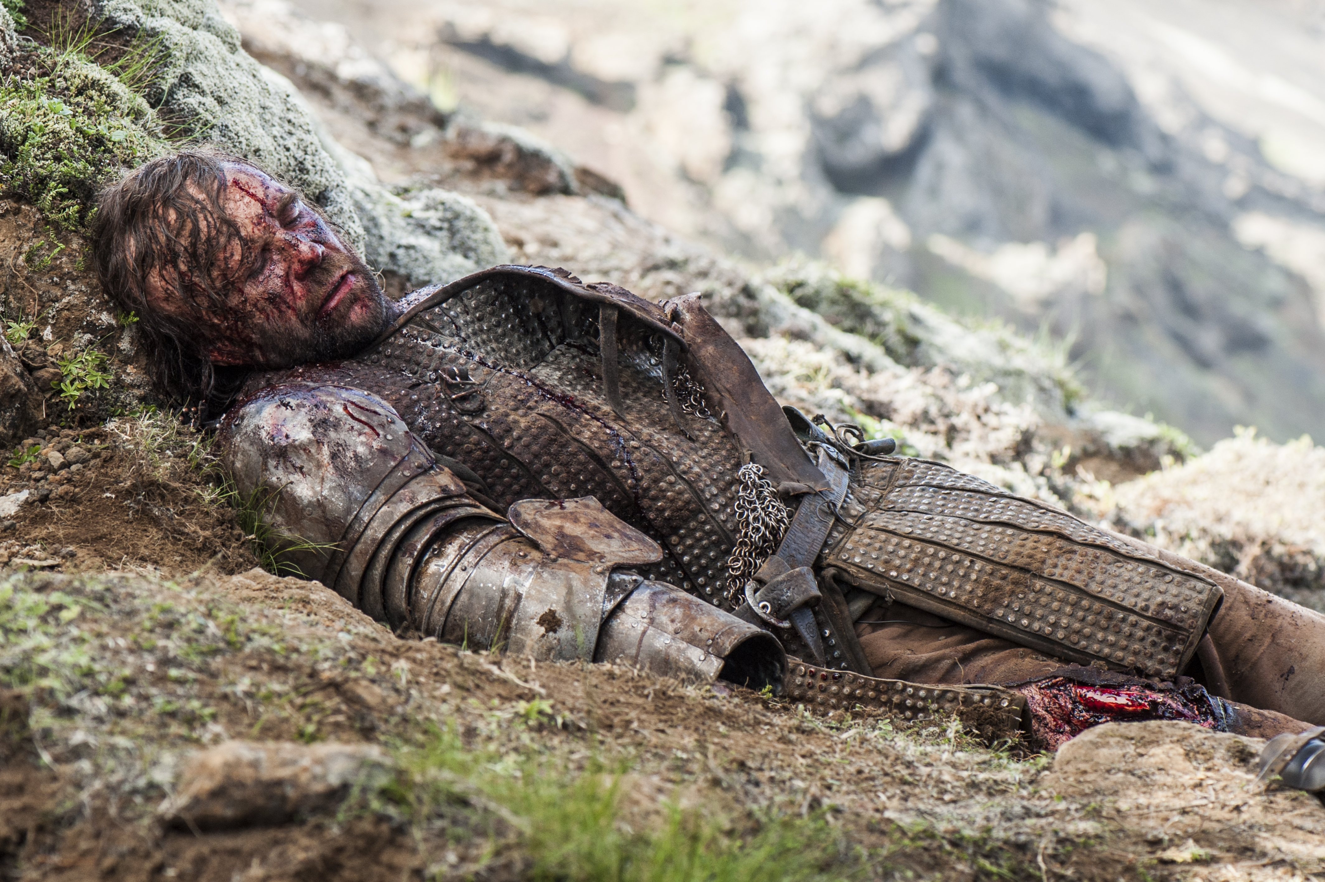 Sandor Clegane lying injured on a rocky slope HD Wallpaper