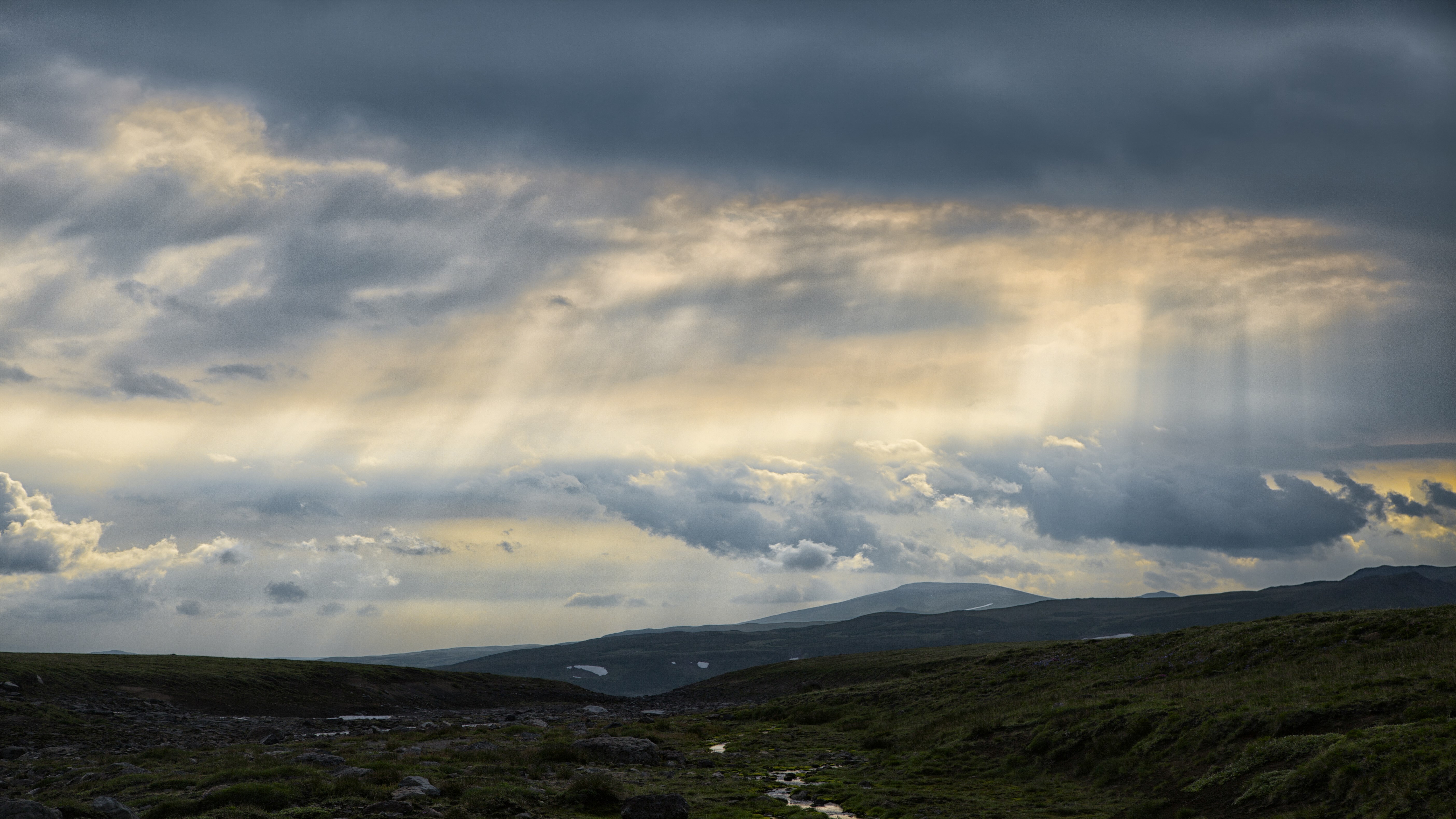 Sunbeams through clouds over a mountainous landscape HD Wallpaper