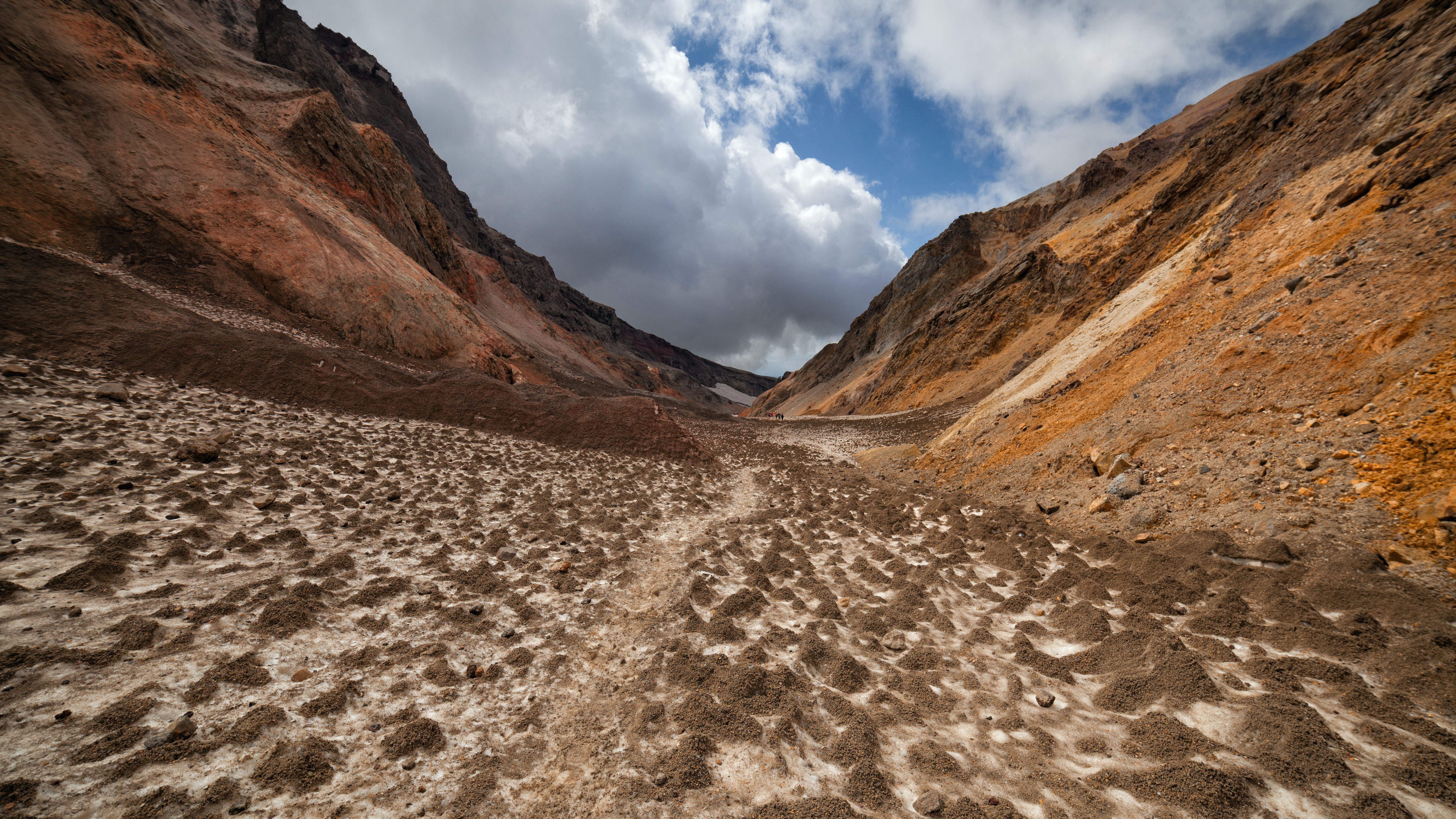 Volcanic valley with rocky slopes and cloudy sky HD Wallpaper