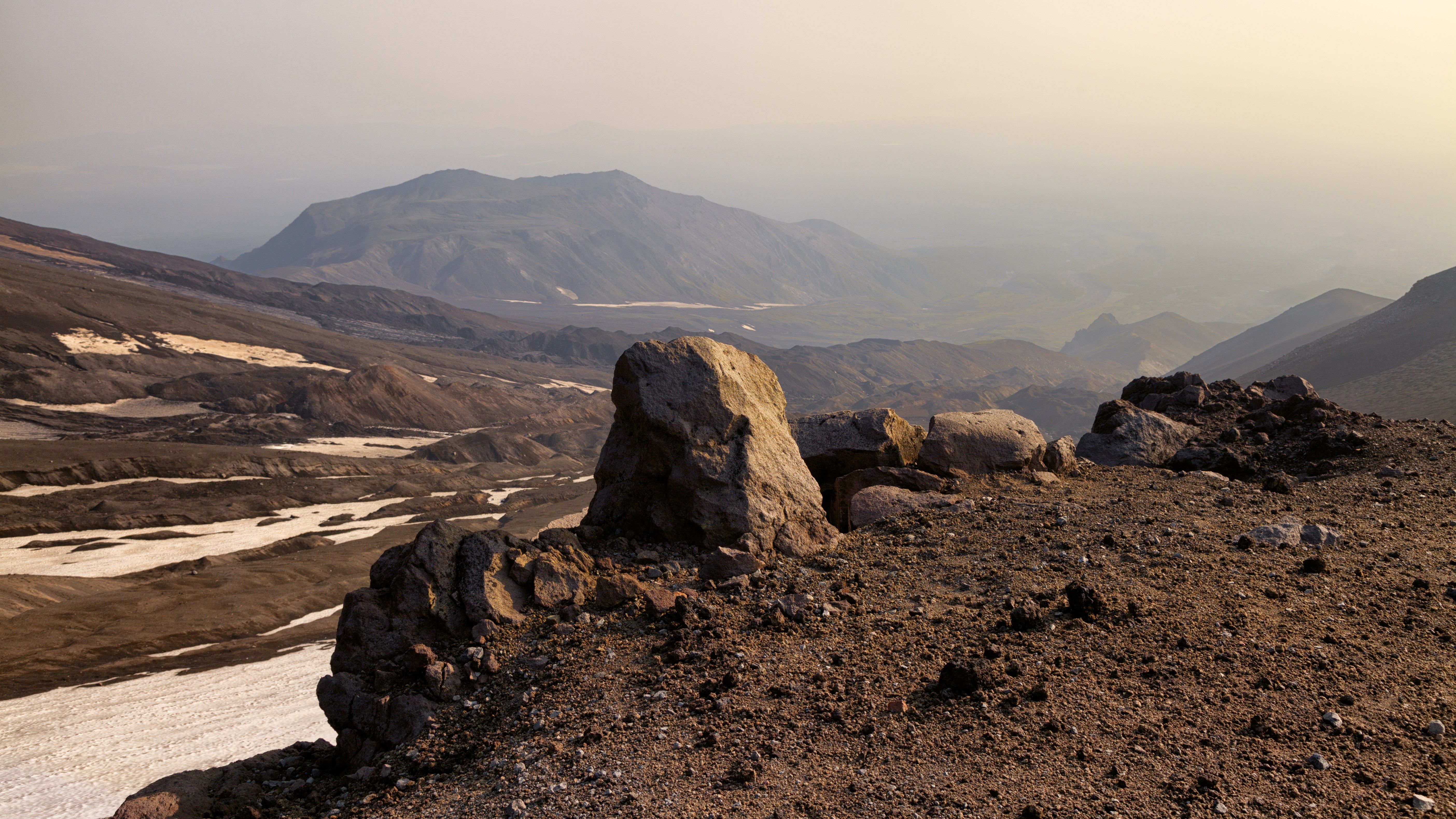 Rocky volcanic landscape with distant mountains HD Wallpaper