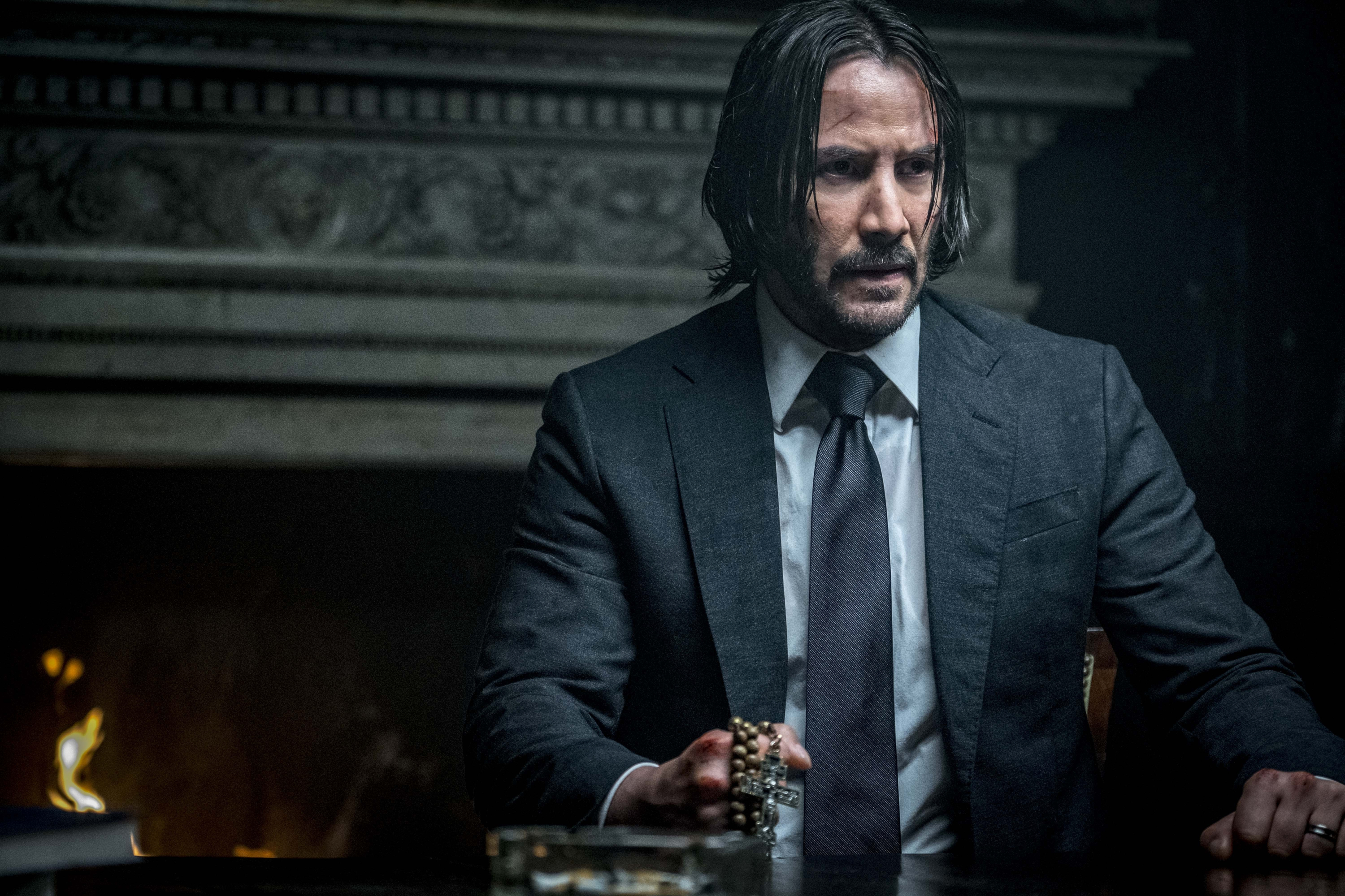 John Wick in a Suit Holding Rosary Beads HD Wallpaper