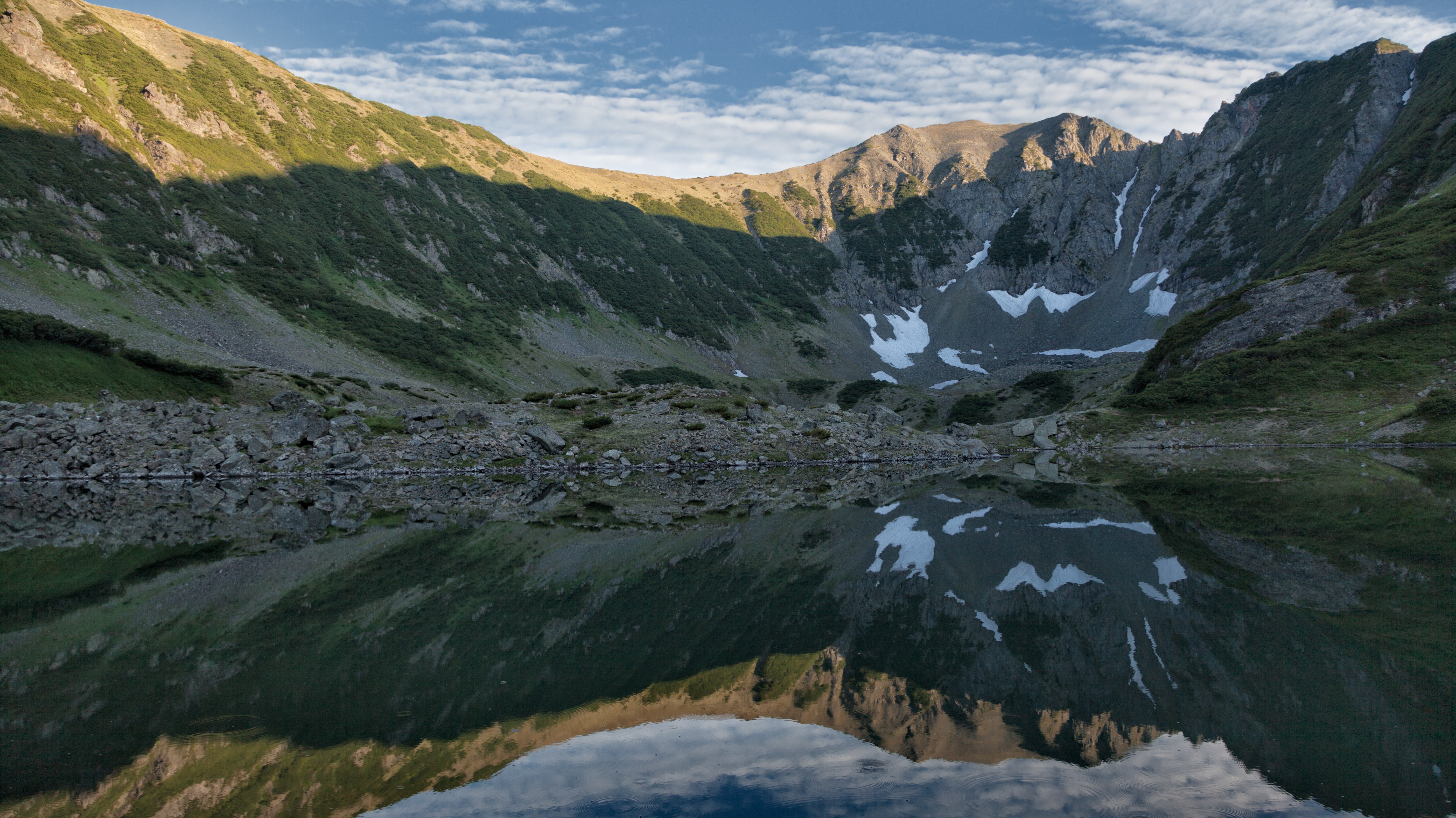 Mountain lake reflecting rocky slopes and sky HD Wallpaper