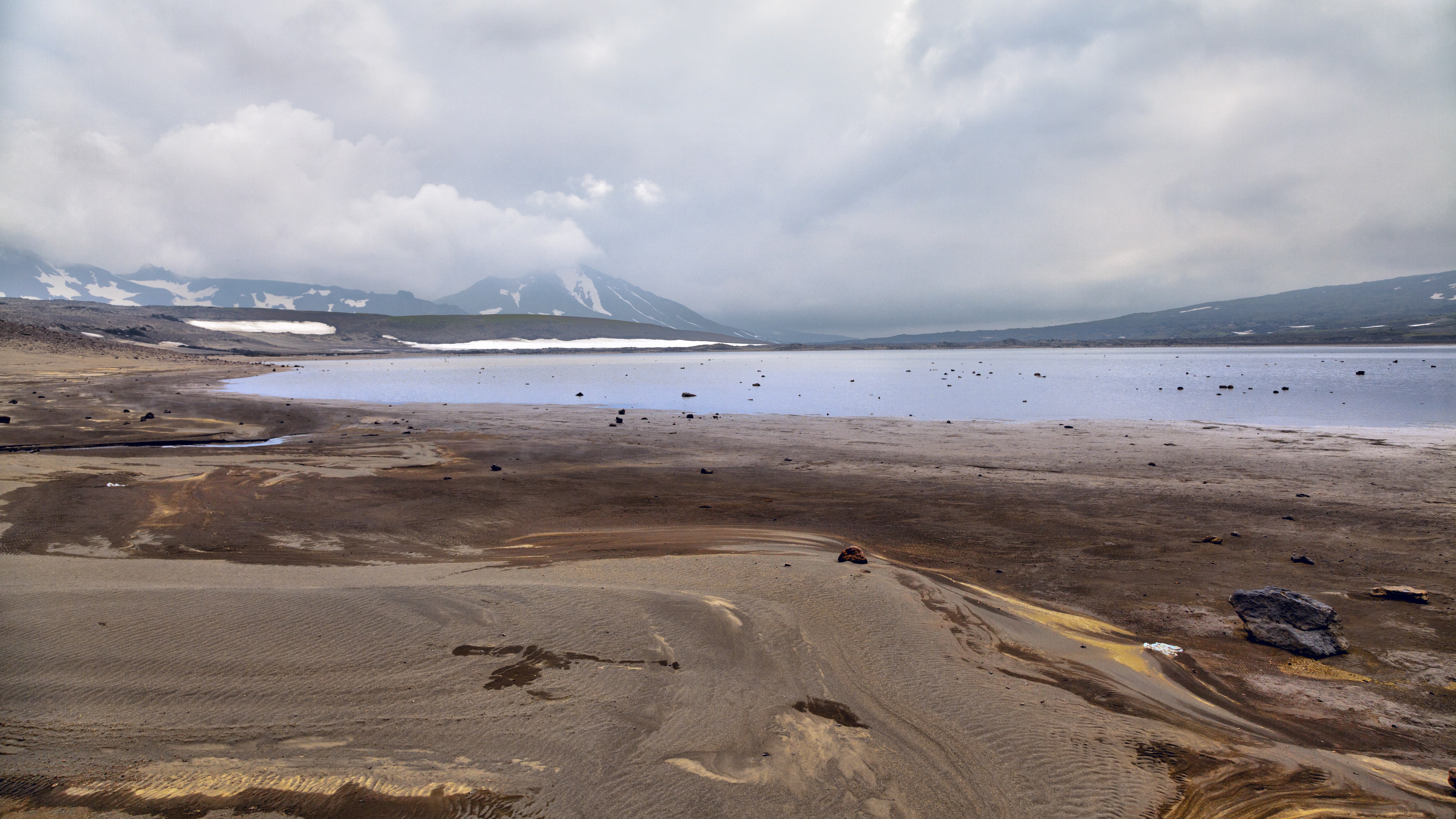 Volcanic lake shore with mountains and clouds HD Wallpaper
