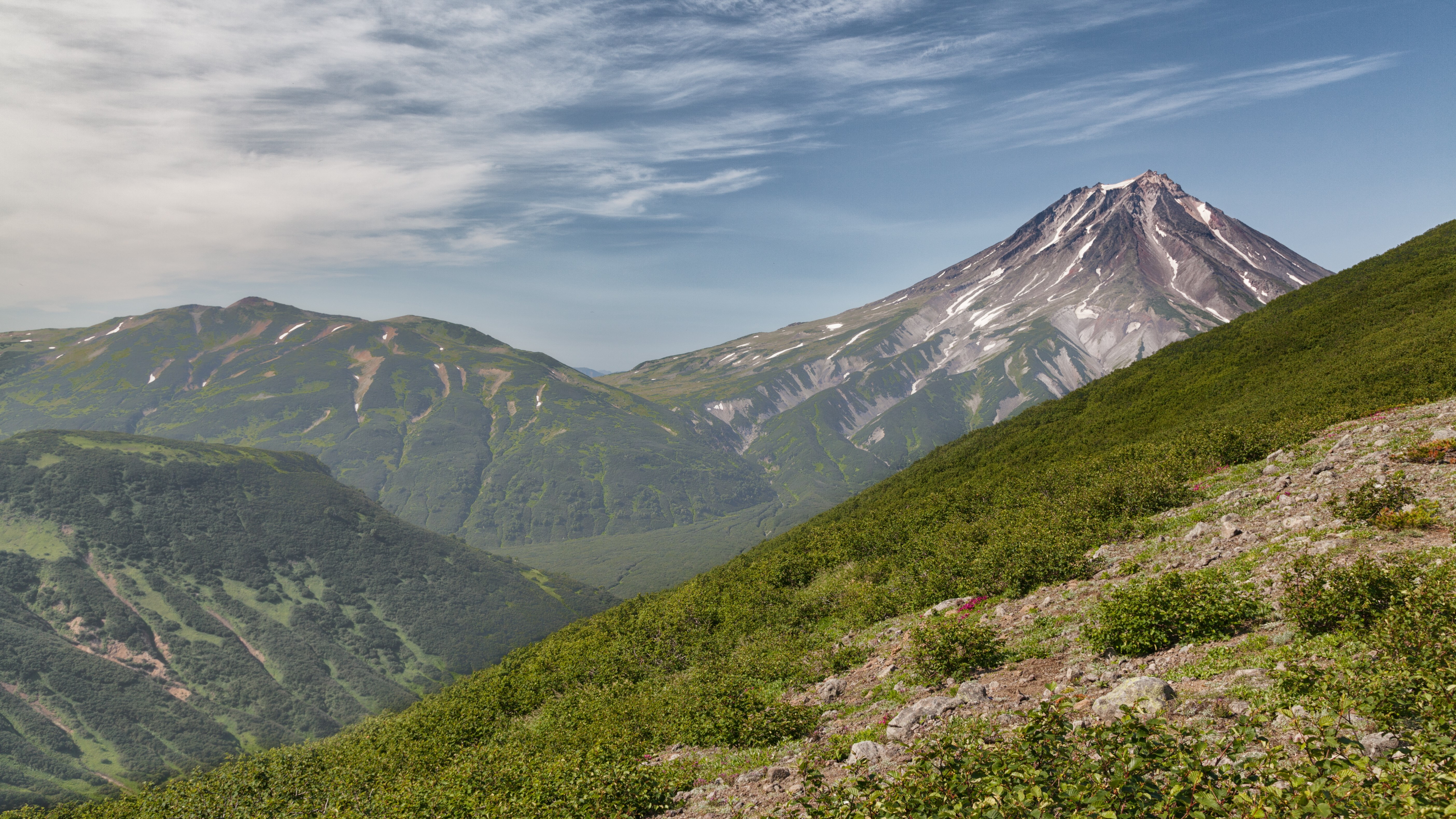 Volcano and green mountains under a cloudy sky HD Wallpaper
