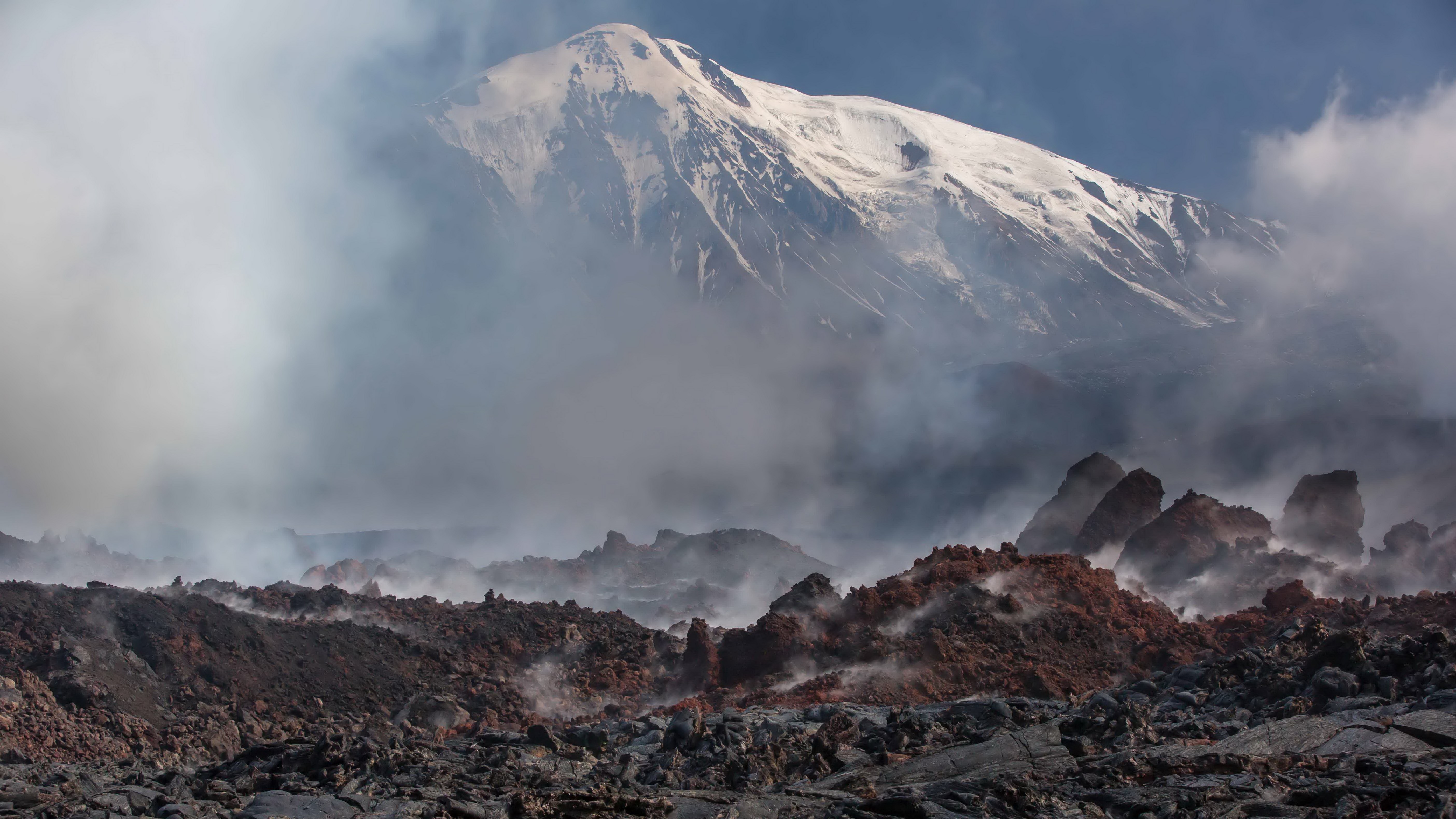 Volcanic landscape with snow-capped mountain and steam HD Wallpaper