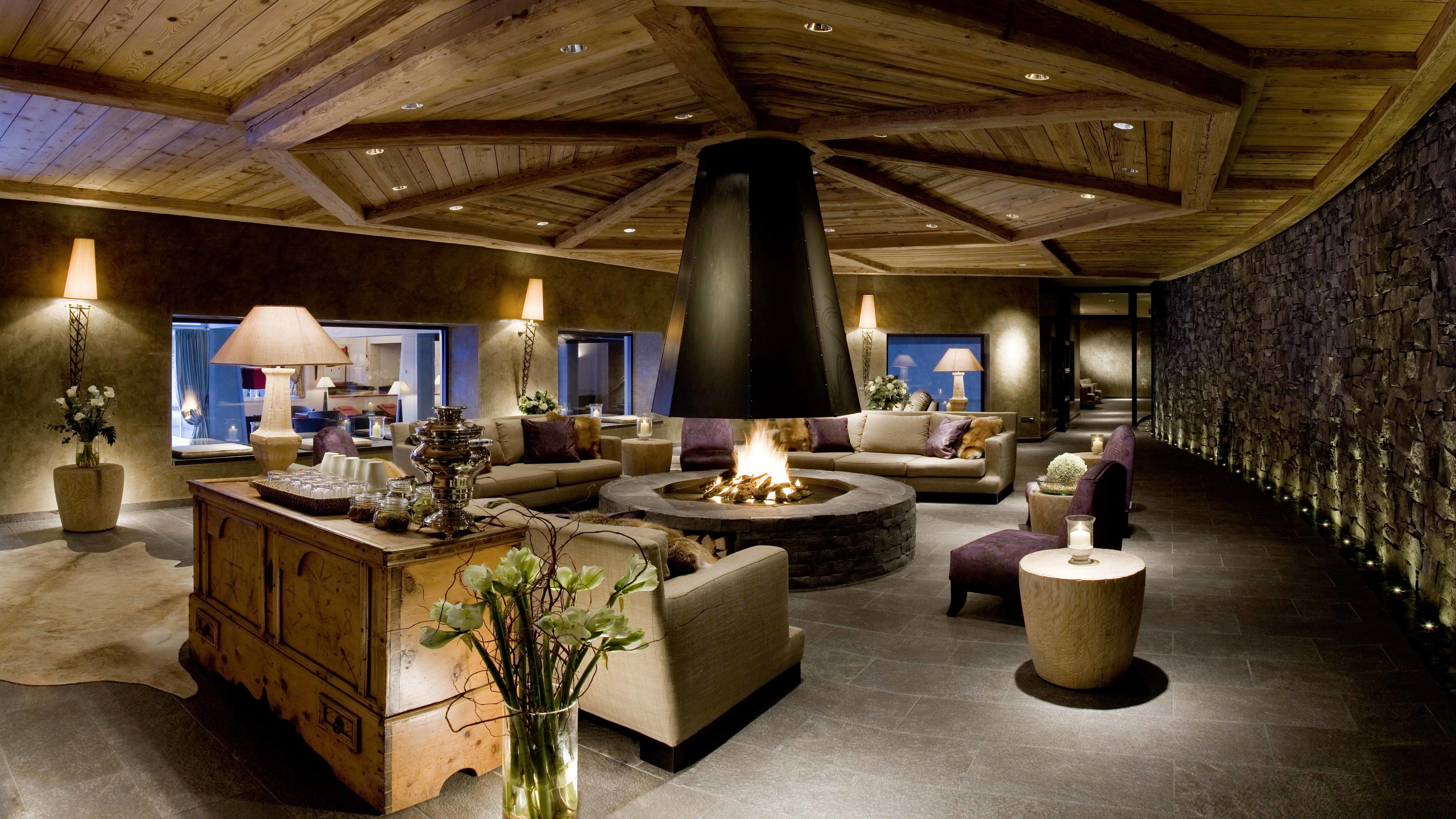 Luxury hotel lobby with central fireplace and seating HD Wallpaper