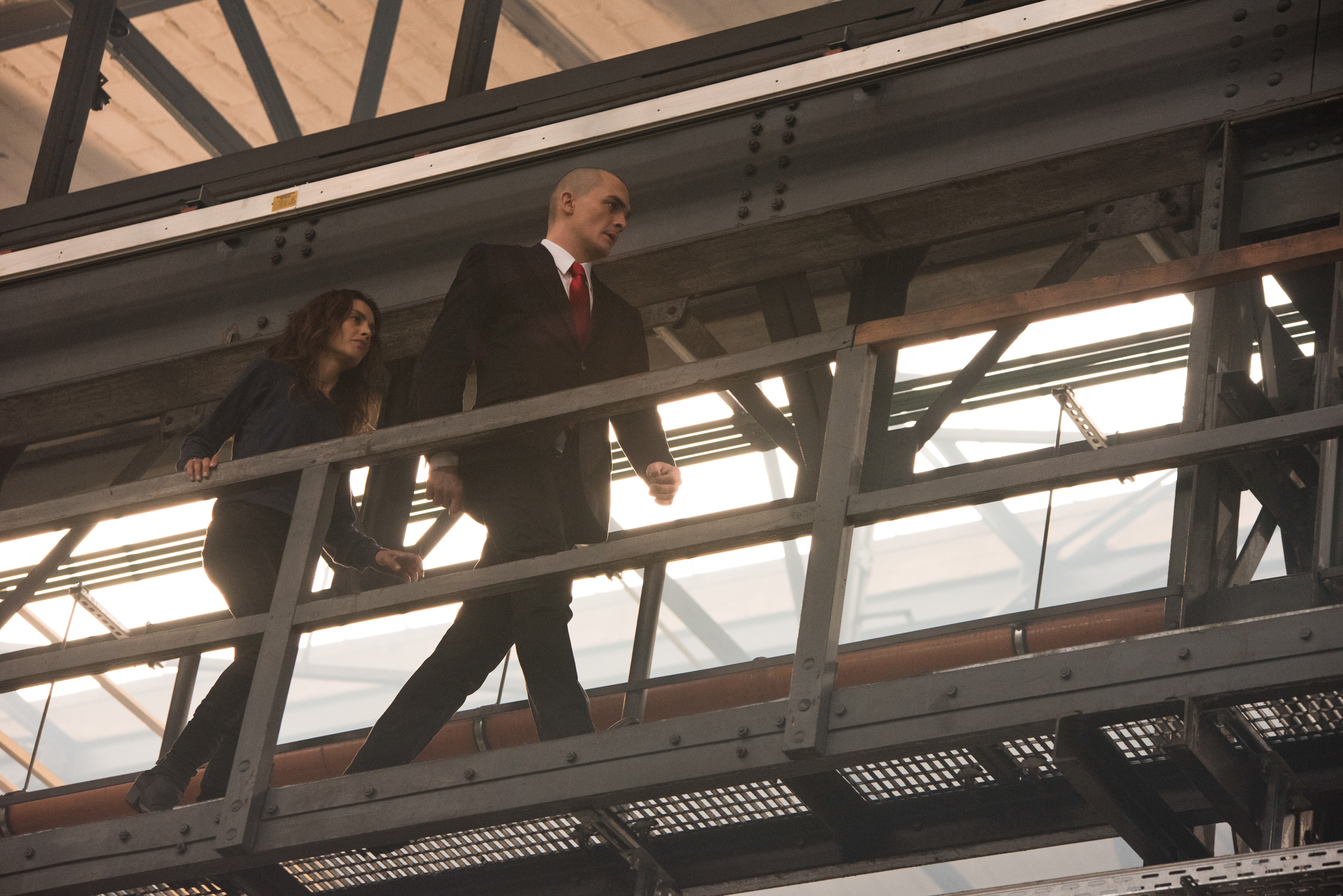 Agent 47 and woman on walkway HD Wallpaper