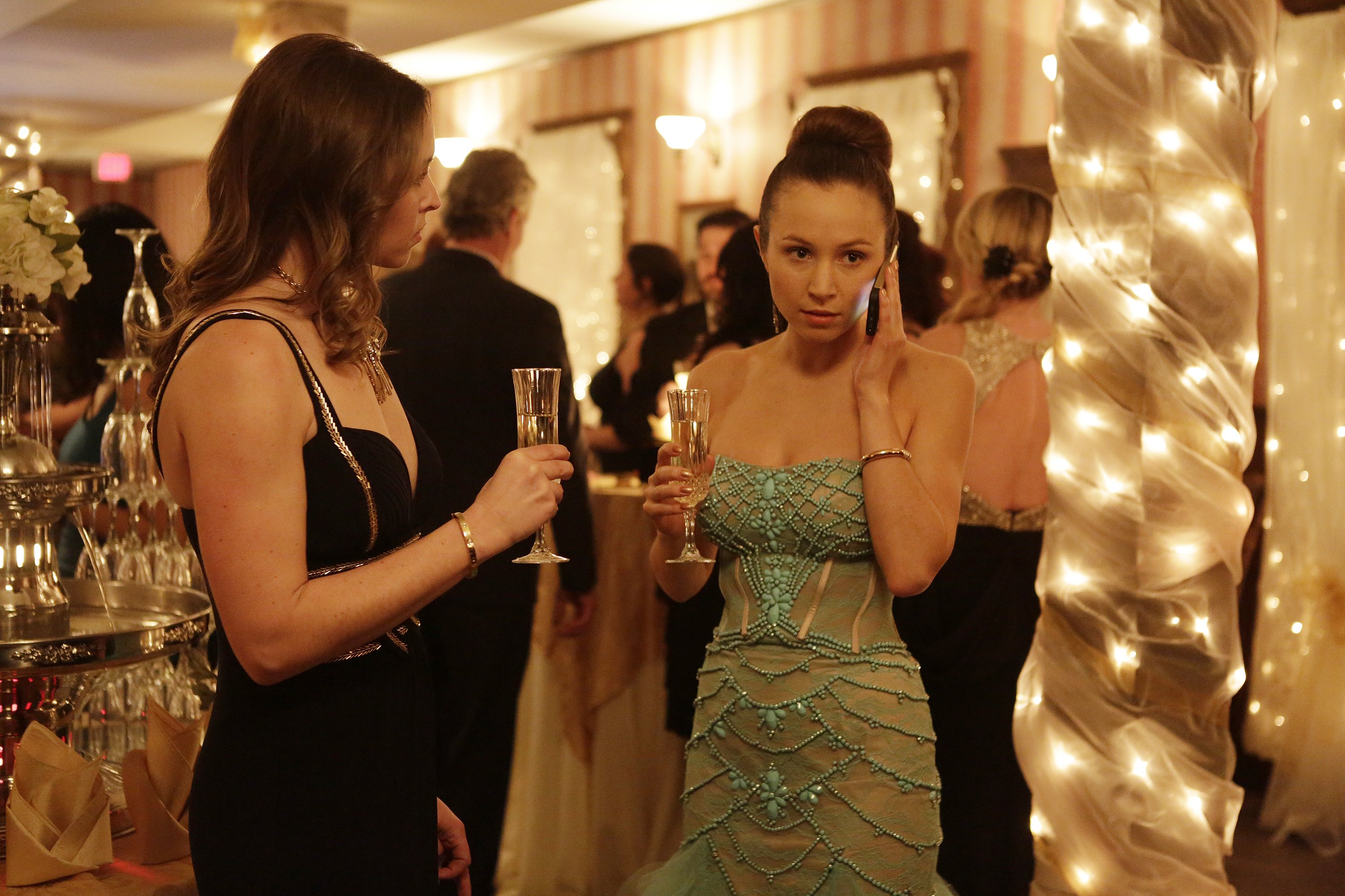 Woman in a teal dress talking on a phone at a party HD Wallpaper