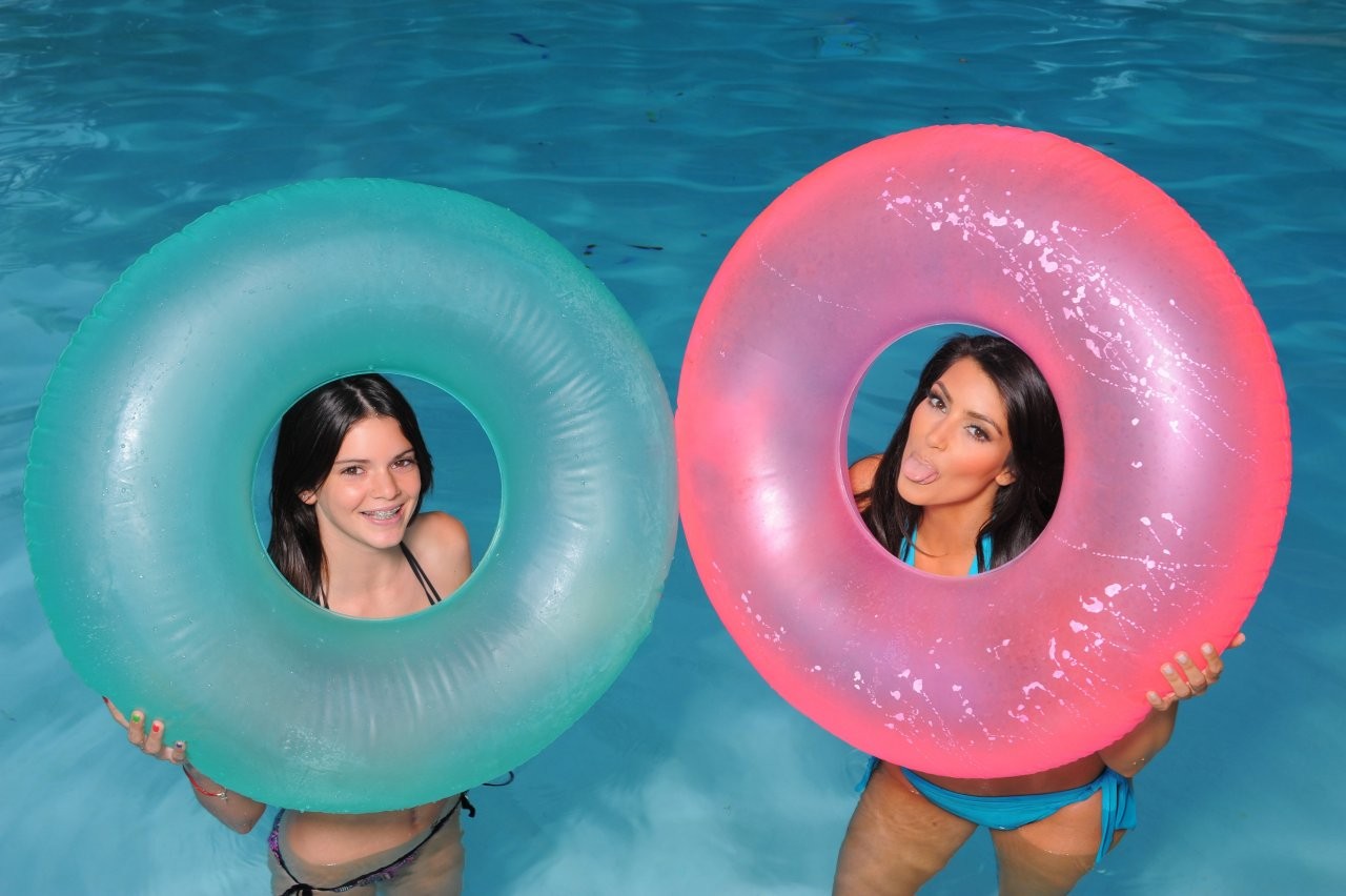 Kim Kardashian and Kendall Jenner with inflatable tubes in a pool HD Wallpaper