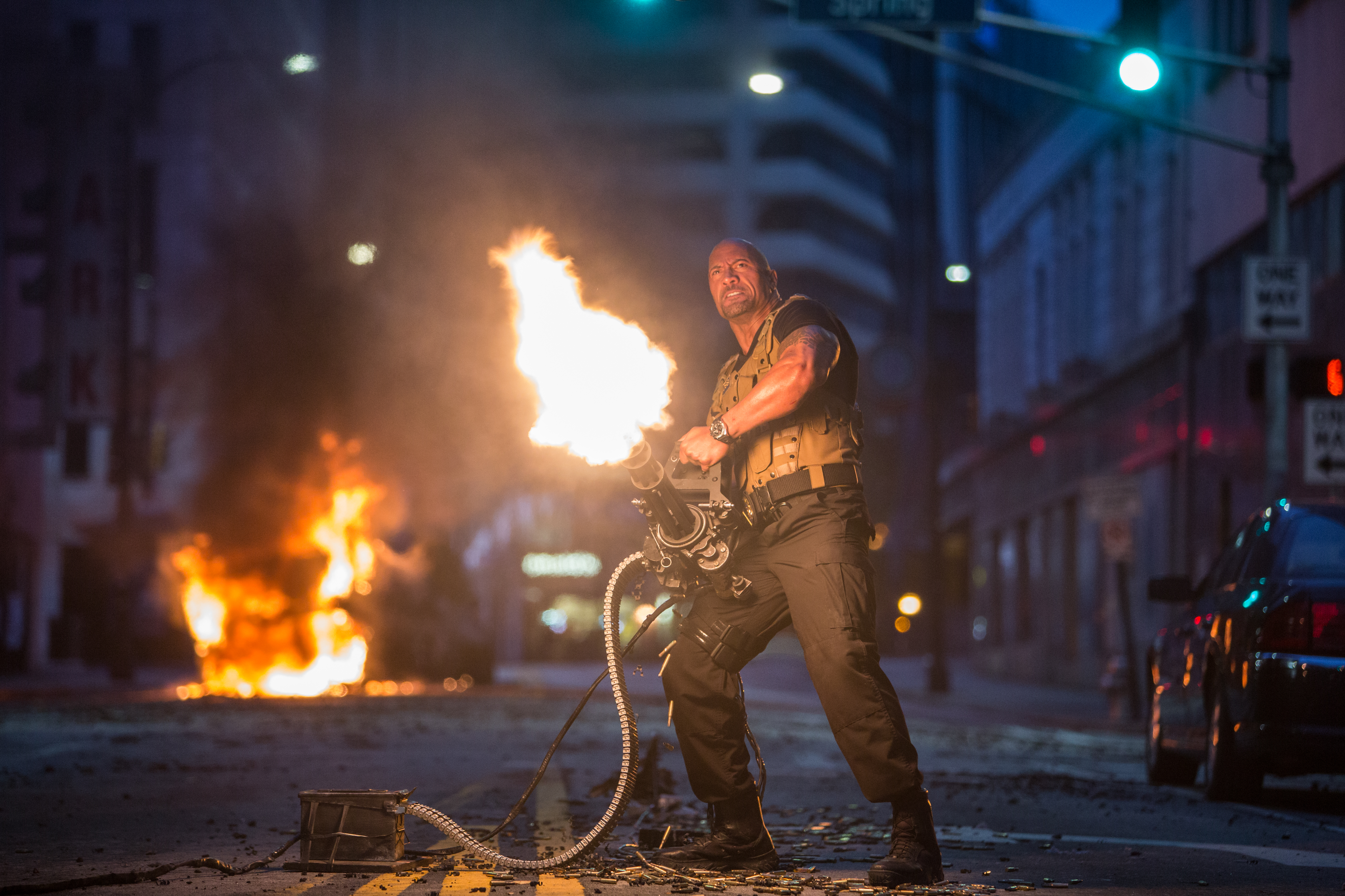 Luke Hobbs firing a minigun in a city at night HD Wallpaper