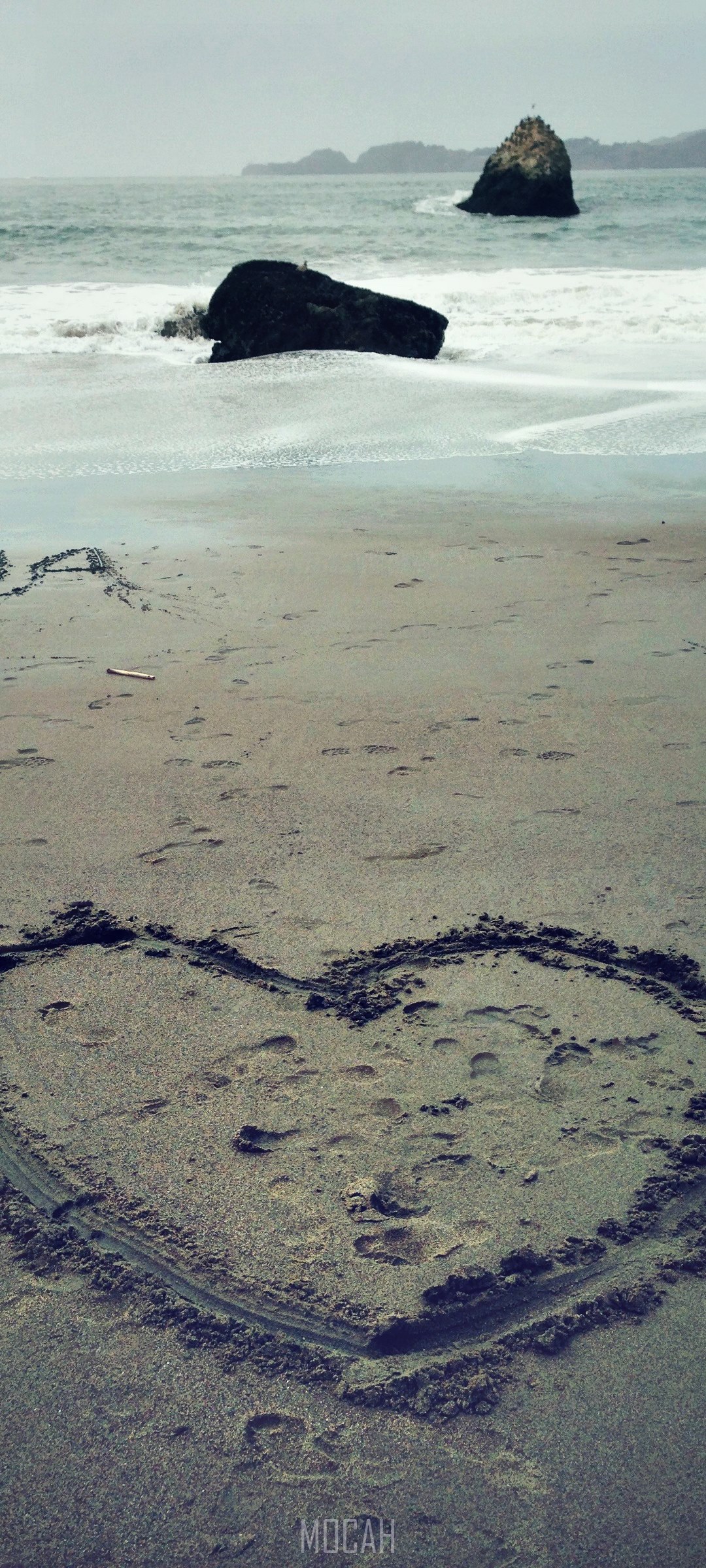 Heart drawn in sand on a beach with rocks in the ocean HD Phone Wallpaper