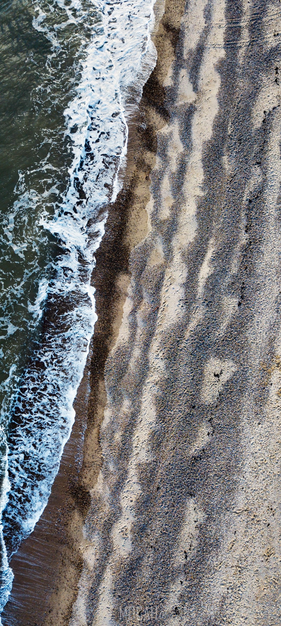 Aerial view of waves crashing on a pebble beach HD Phone Wallpaper