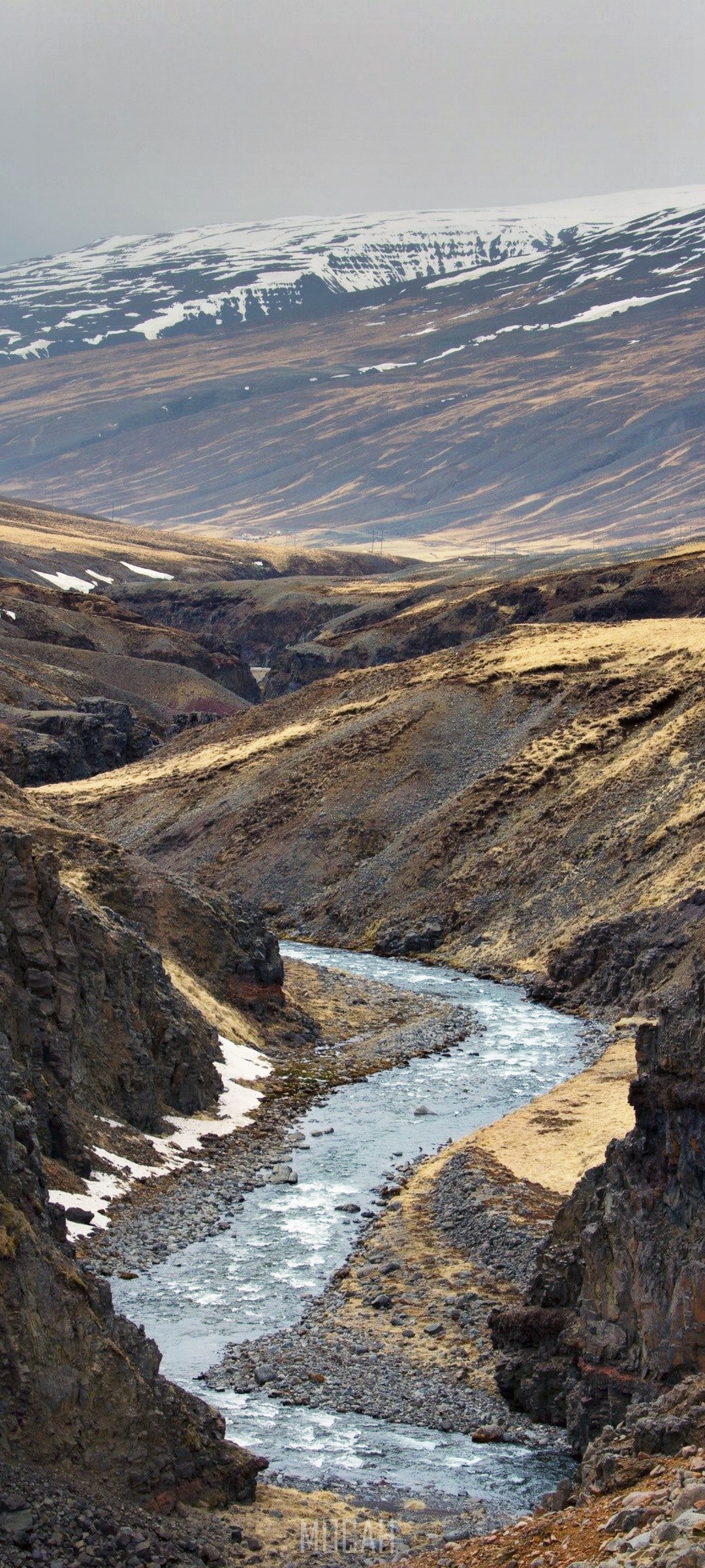 River flowing through a rocky valley with snow-capped mountains HD Phone Wallpaper