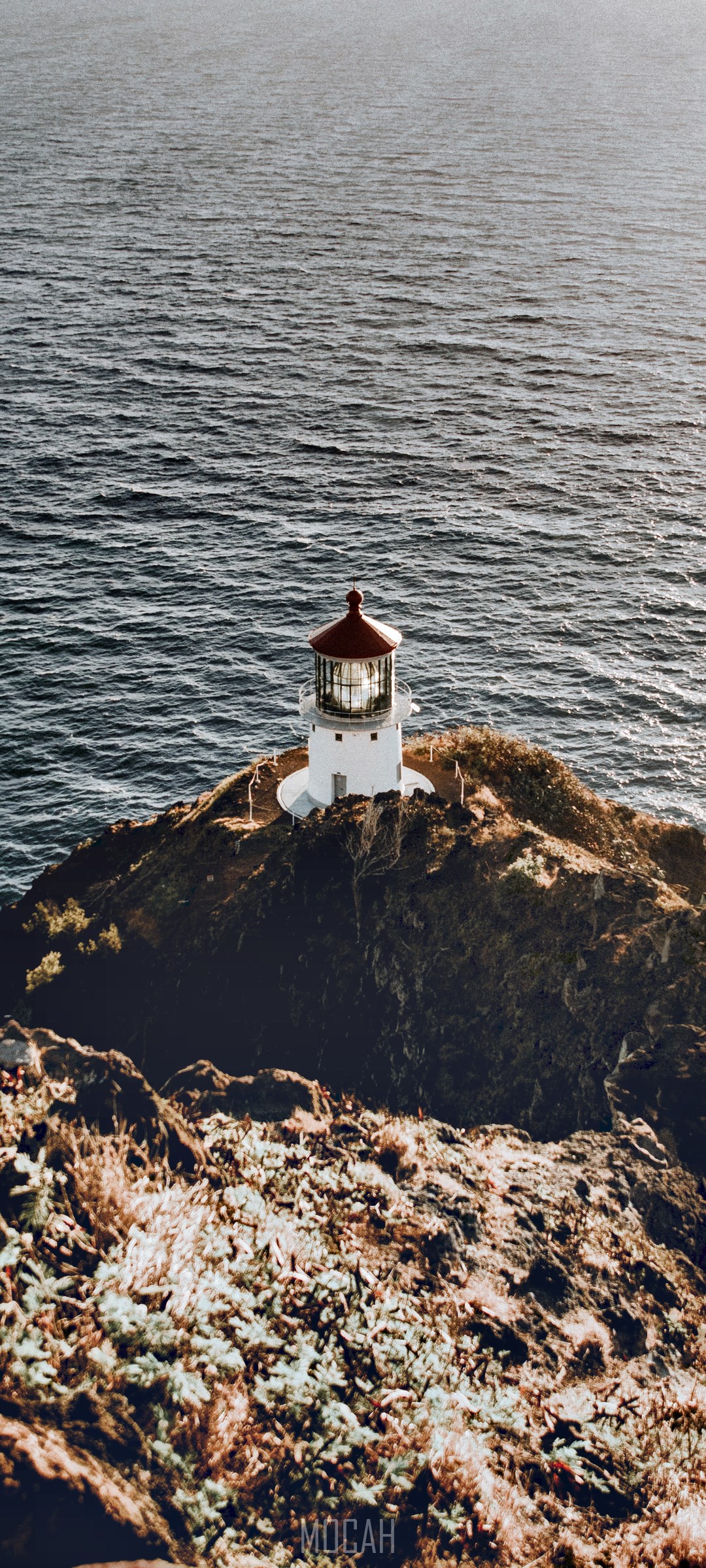 Lighthouse on a rocky cliff overlooking the sea HD Phone Wallpaper
